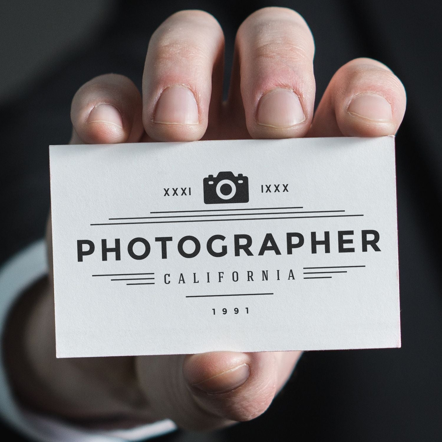 A hand holding a business card stamped with the MaxLight XL2-275 Custom Pre-Inked Business Stamp 2 x 4, displaying Photographer California 1991.