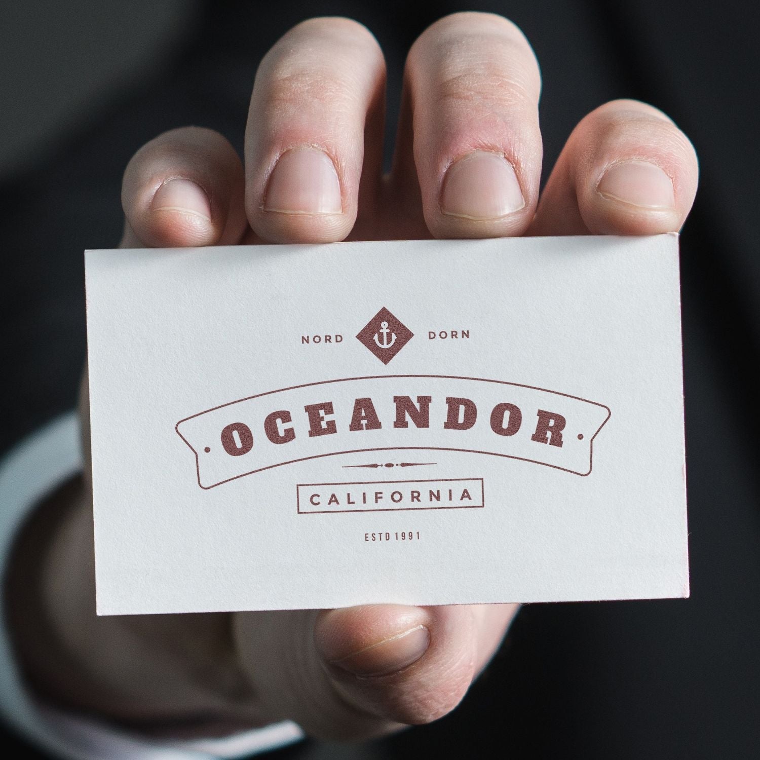 A hand holding a business card stamped with the Custom Self Inking Stamp Trodat 4928 Size 1-5/16 x 2-3/8, displaying Oceandor California.