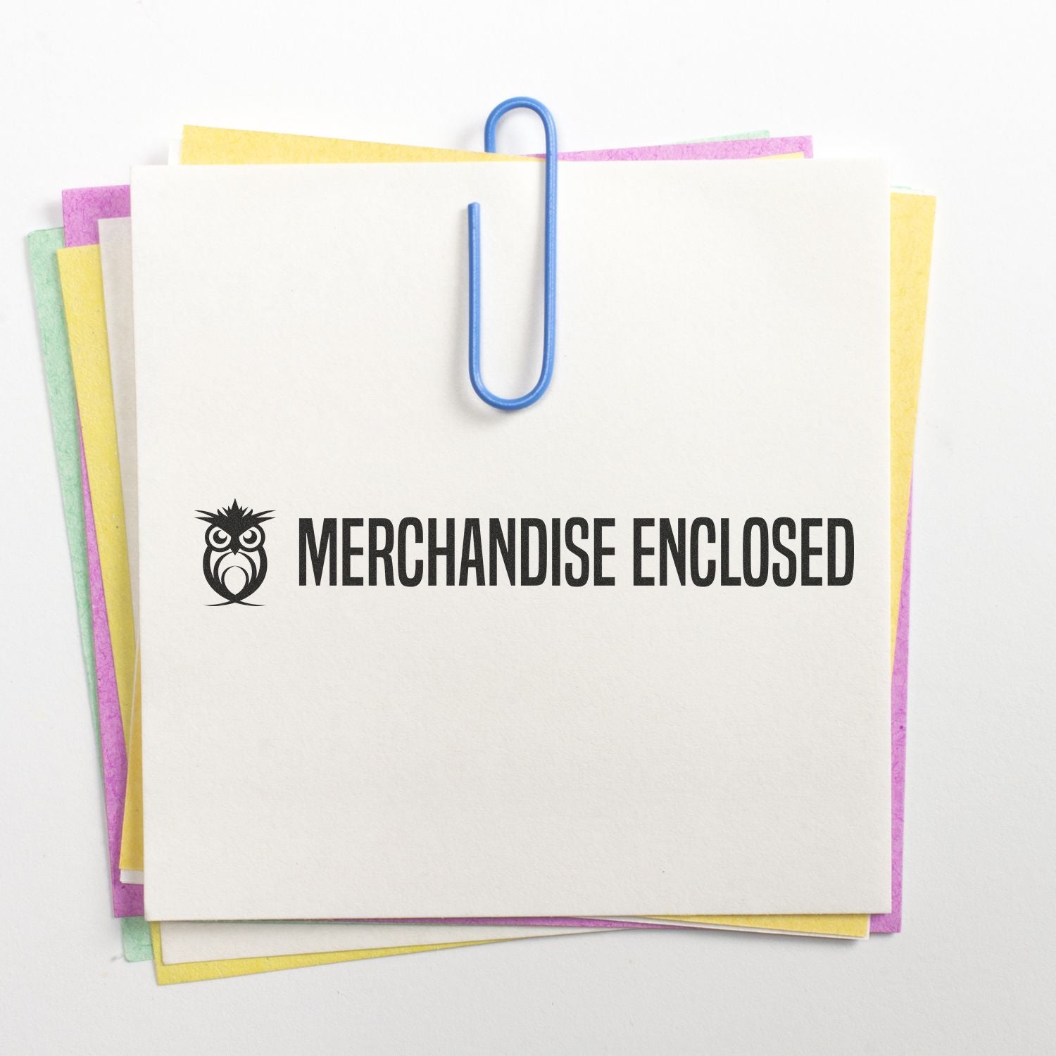 Custom Self Inking Stamp Trodat 4916 Size 3/8 x 2-3/4 stamping MERCHANDISE ENCLOSED on a stack of colorful papers with a blue paperclip.