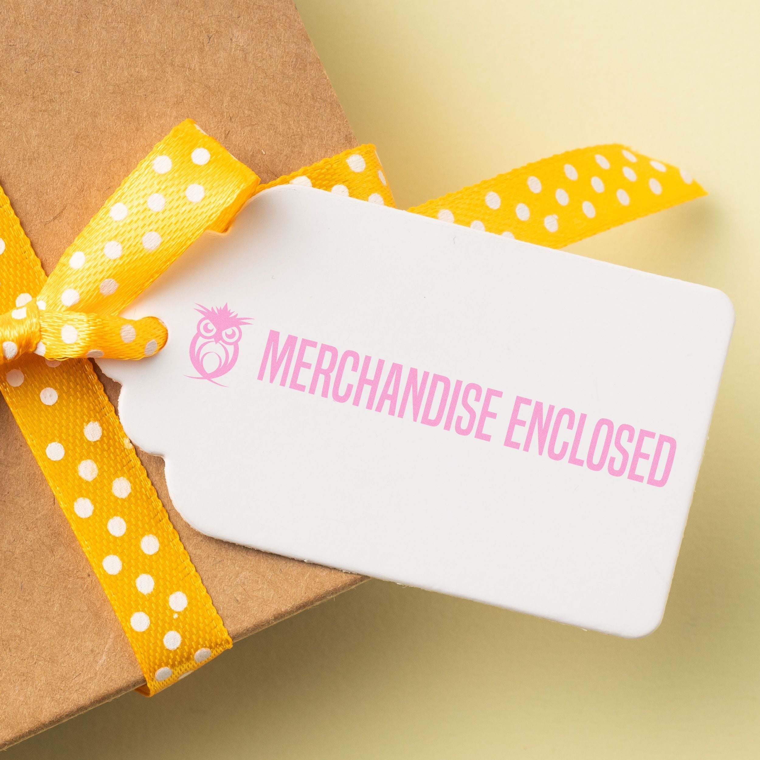 Gift tag stamped with MERCHANDISE ENCLOSED using Custom Self Inking Stamp Trodat 4918 Size 5/8 x 3, attached to a box with a yellow polka dot ribbon.