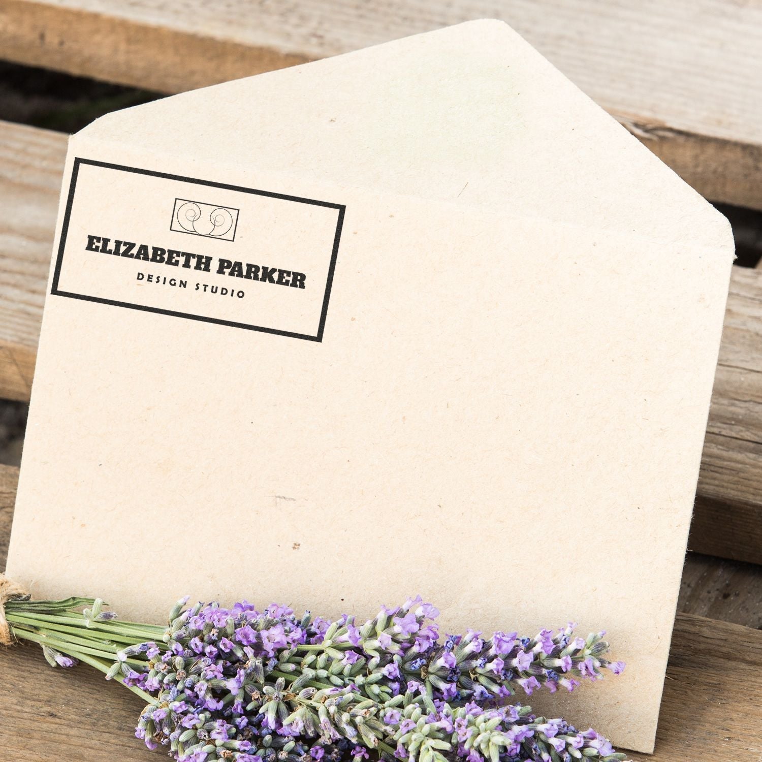 Envelope stamped with MaxLight XL2-750 Custom Pre-Inked Business Stamp 1-1/2 x 4-1/3, next to a bundle of lavender flowers on a wooden surface.