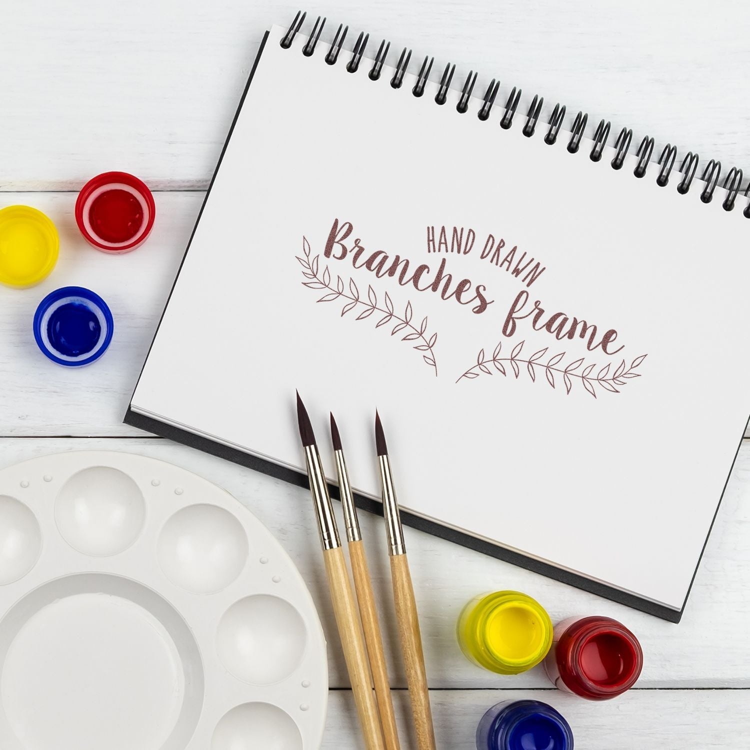 Custom Rubber Stamp Size 2 x 7 used on a sketchbook page with Hand Drawn Branches Frame text, surrounded by paint jars and brushes.