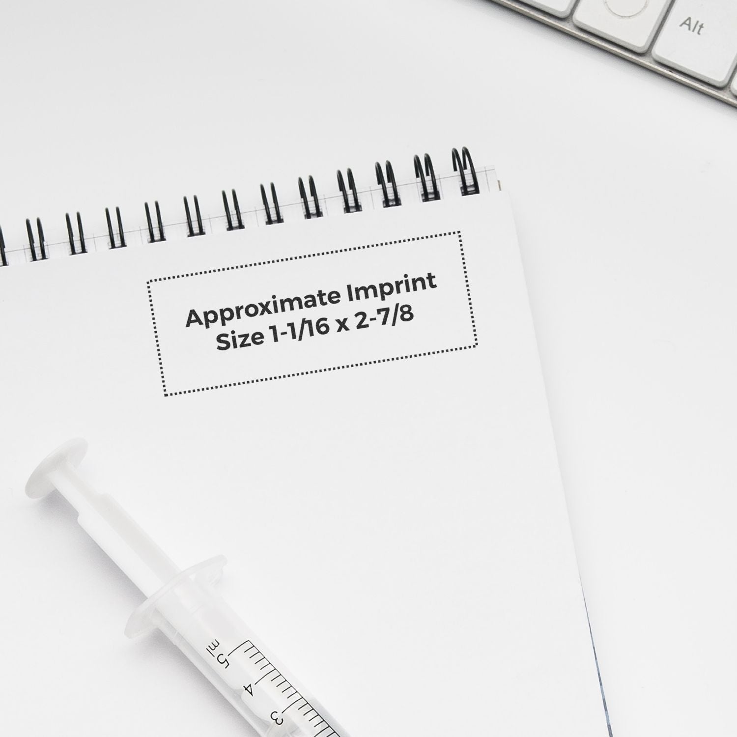 MaxLight XL2-185 Custom Pre-Inked Business Stamp 15/16 x 2-3/4 on a white notepad with a syringe and keyboard nearby.