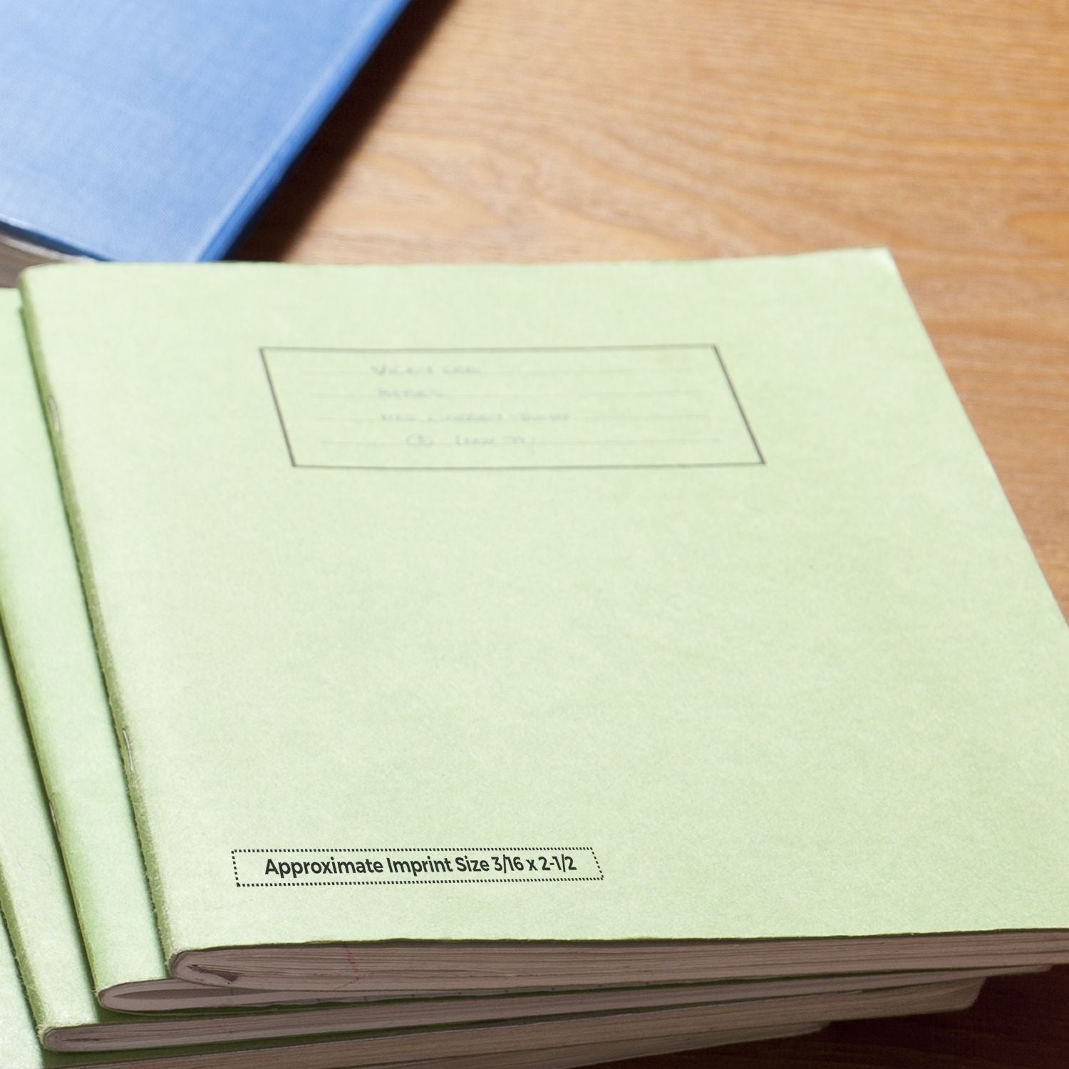 MaxLight XL2-55 Custom Pre-Inked Business Stamp 3/16 x 2-1/2 imprint on a green folder on a wooden desk with a blue folder in the background.