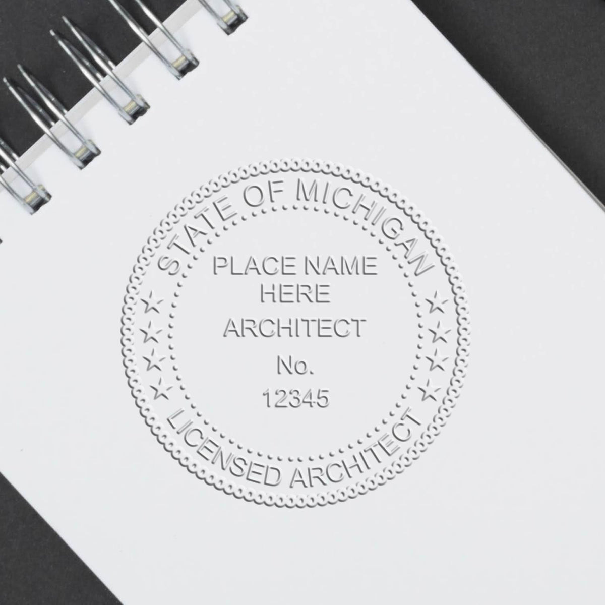 A lifestyle photo showing a stamped image of the Handheld Michigan Architect Seal Embosser on a piece of paper