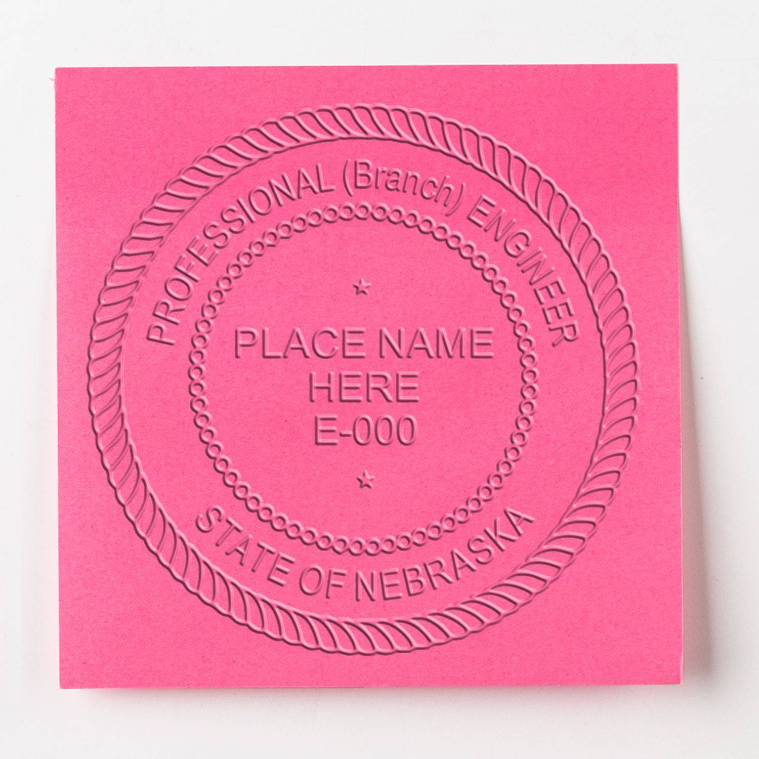 A pink paper embossed with the Professional Engineer Blue Soft Seal Embosser, displaying a circular design with text 'Professional (Branch) Engineer, Place Name Here, E-000, State of Nebraska'.