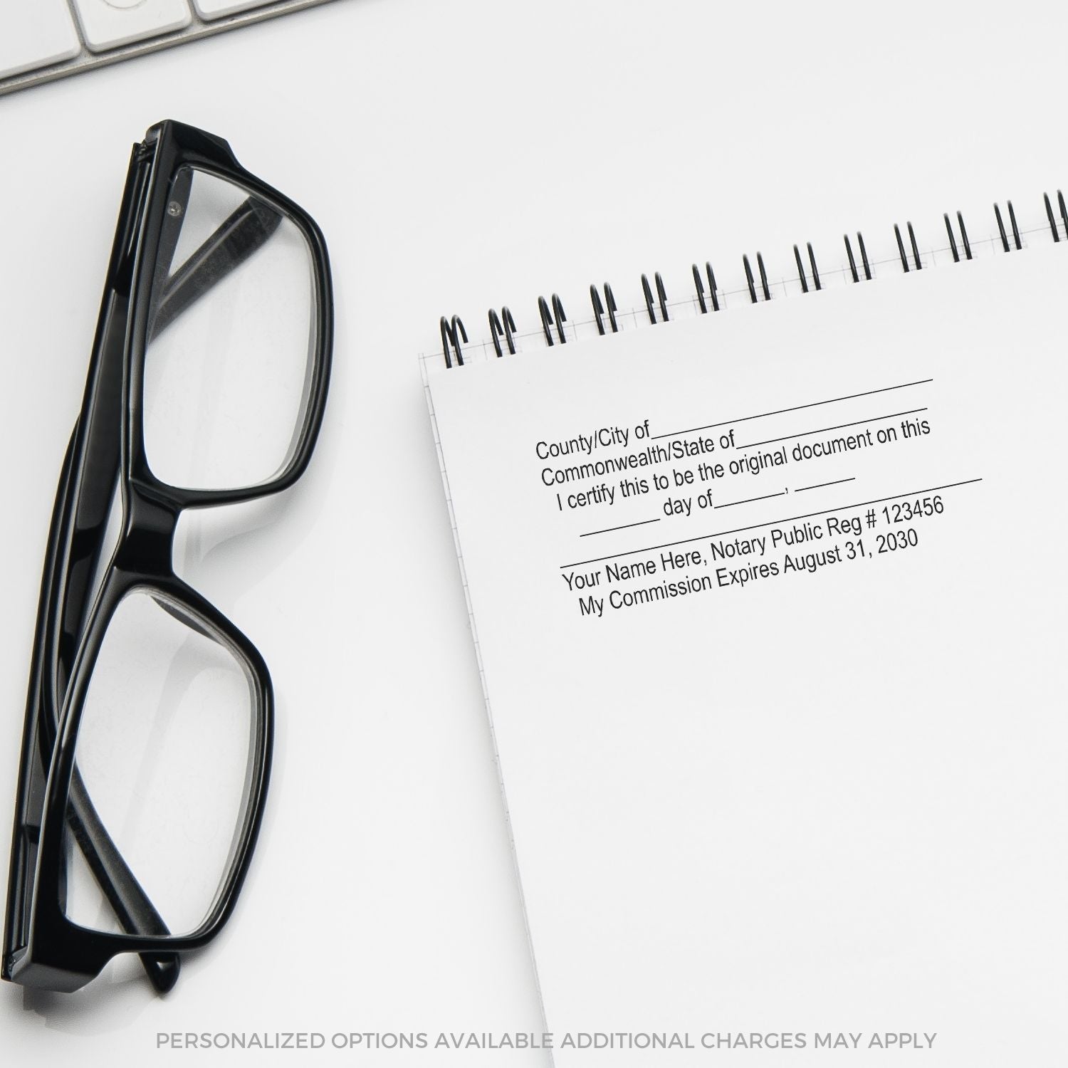 Black Slim Pre-Inked Original Document Stamp on a notepad with text, next to black eyeglasses on a white surface.