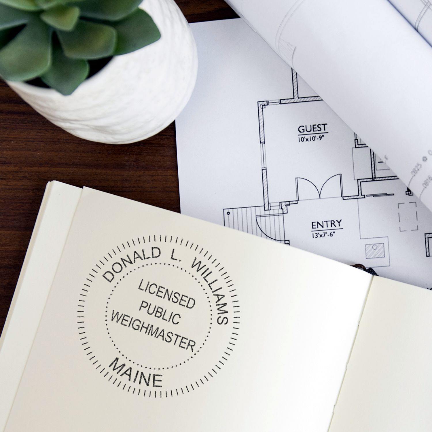 Public Weighmaster Slim Pre-Inked Rubber Stamp of Seal used on a document, with a plant and architectural plans in the background.