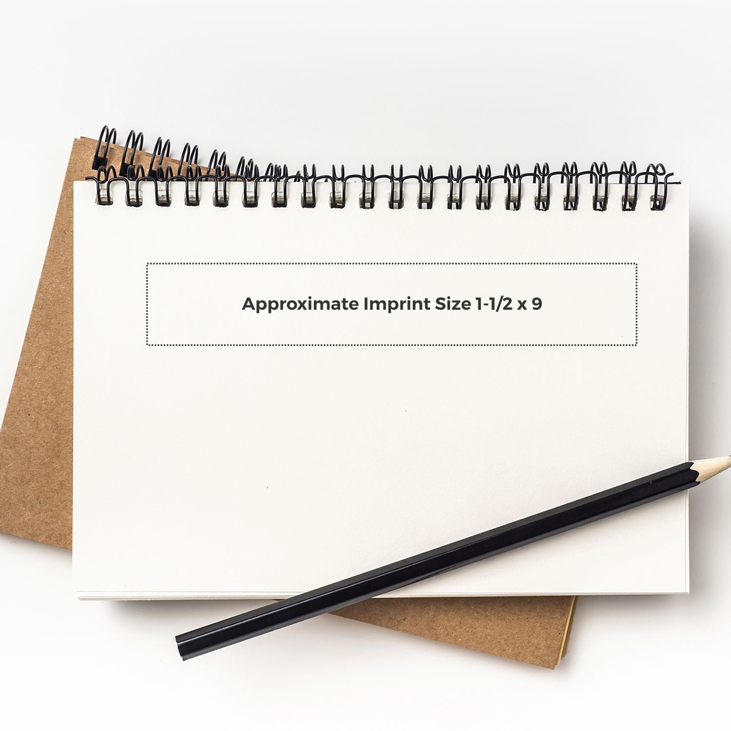 Custom Rubber Stamp Size 1-1/2 x 9 displayed on a spiral notebook with a pencil and a brown cover notebook in the background.