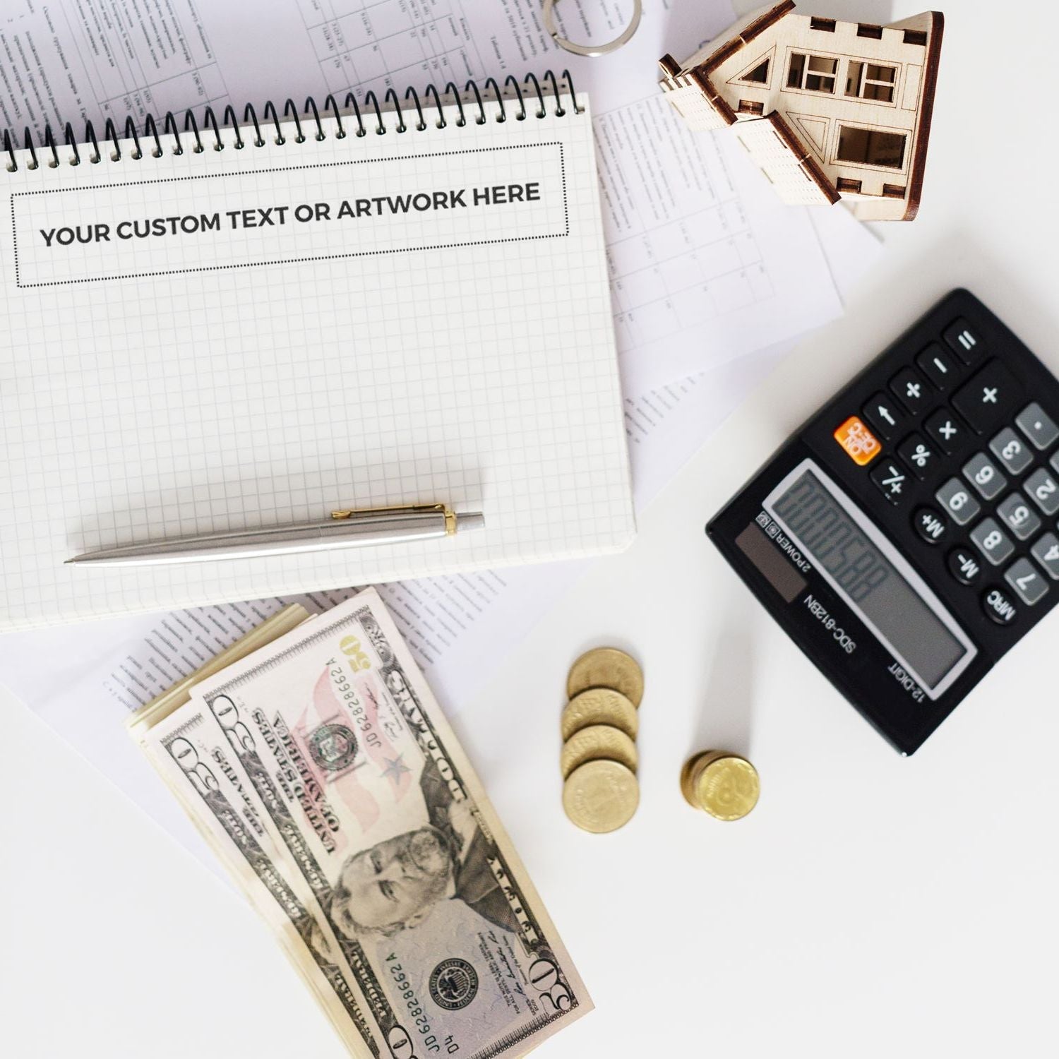 Custom Rubber Stamp Size 1-1/2 x 9 stamped on a notepad, surrounded by a pen, calculator, cash, coins, and a small wooden house model.