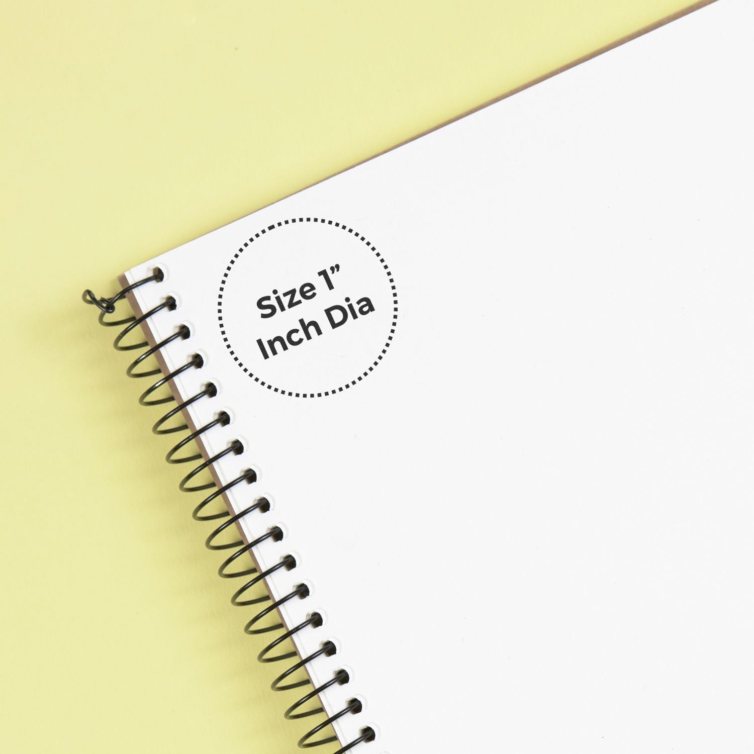Custom Rubber Stamp Size 1 Inch Diameter stamped on a white spiral notebook with a yellow background.