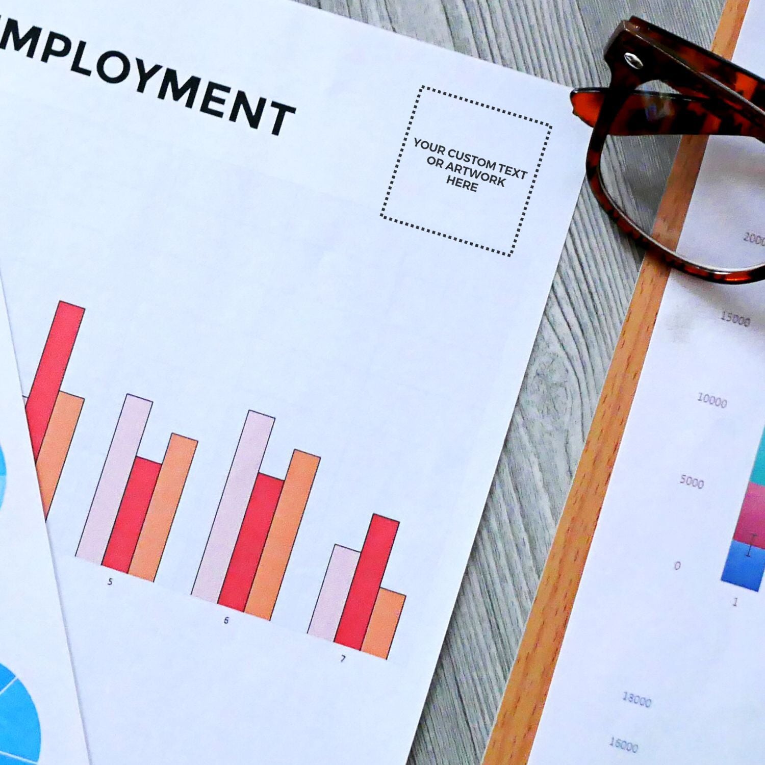 Employment document stamped with Custom Rubber Stamp Size 1 x 1 beside a pair of glasses and colorful bar charts on a wooden surface.
