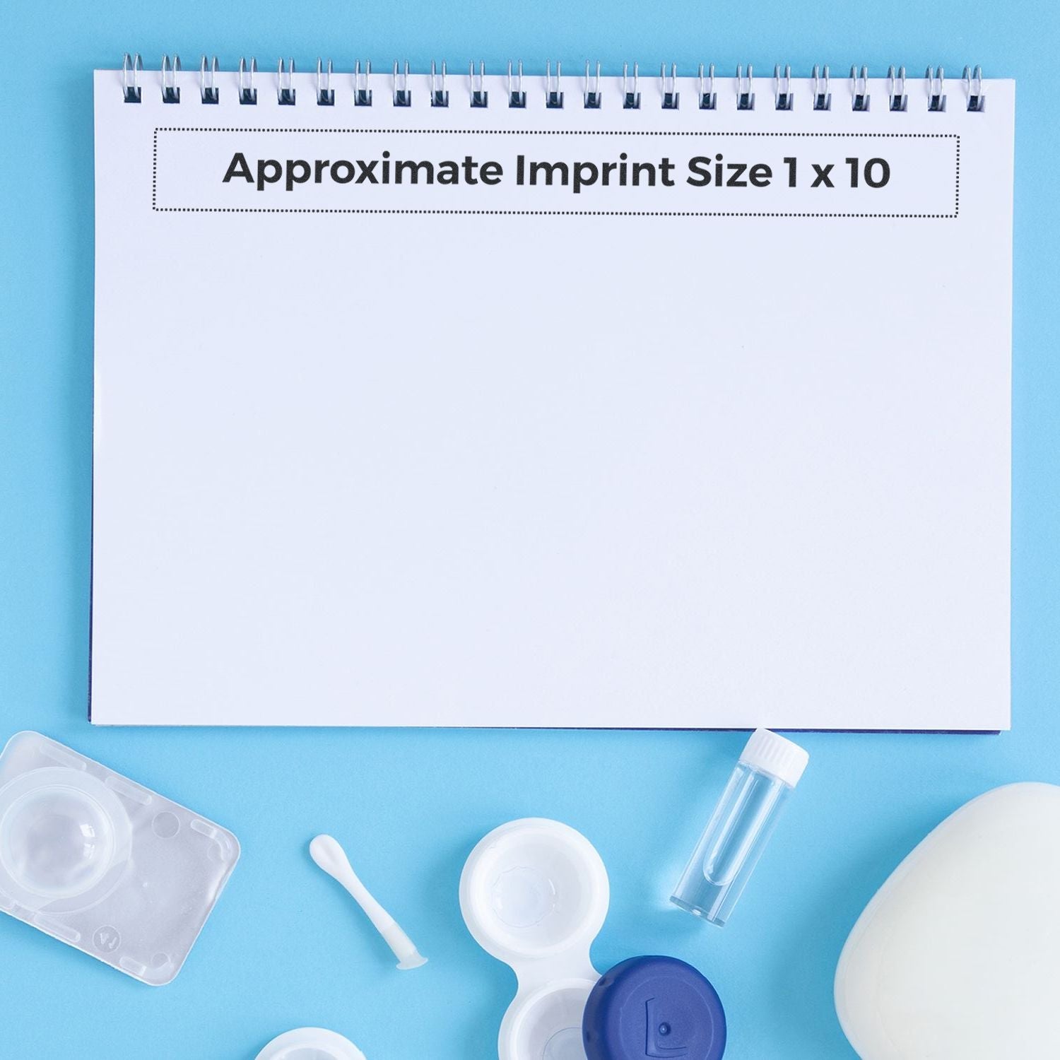 Custom Rubber Stamp Size 1 x 10 displayed on a white notepad with various small plastic containers and a blue background.