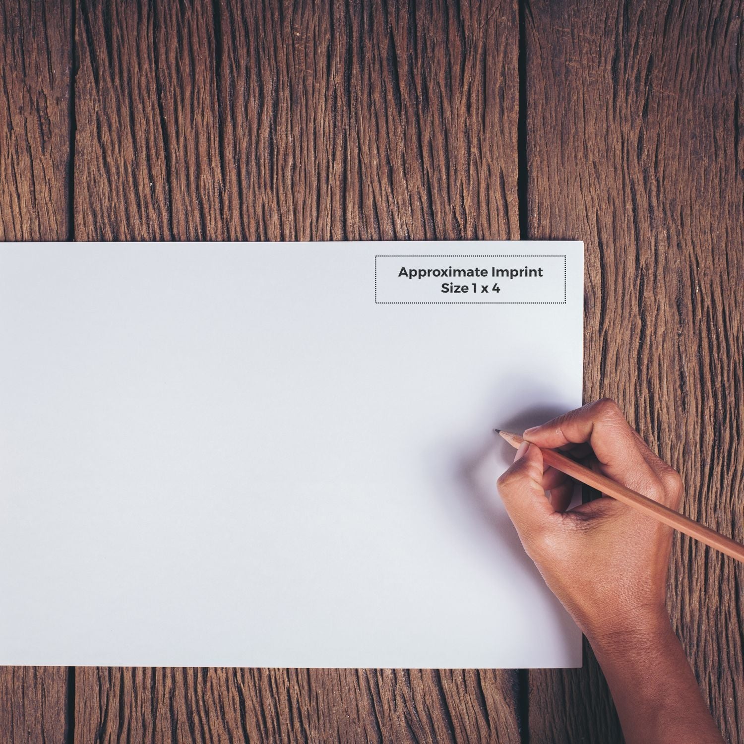 Hand holding pencil near a stamped Approximate Imprint Size 1 x 4 on white paper on wooden surface, showcasing Custom Rubber Stamp Size 1 x 4.