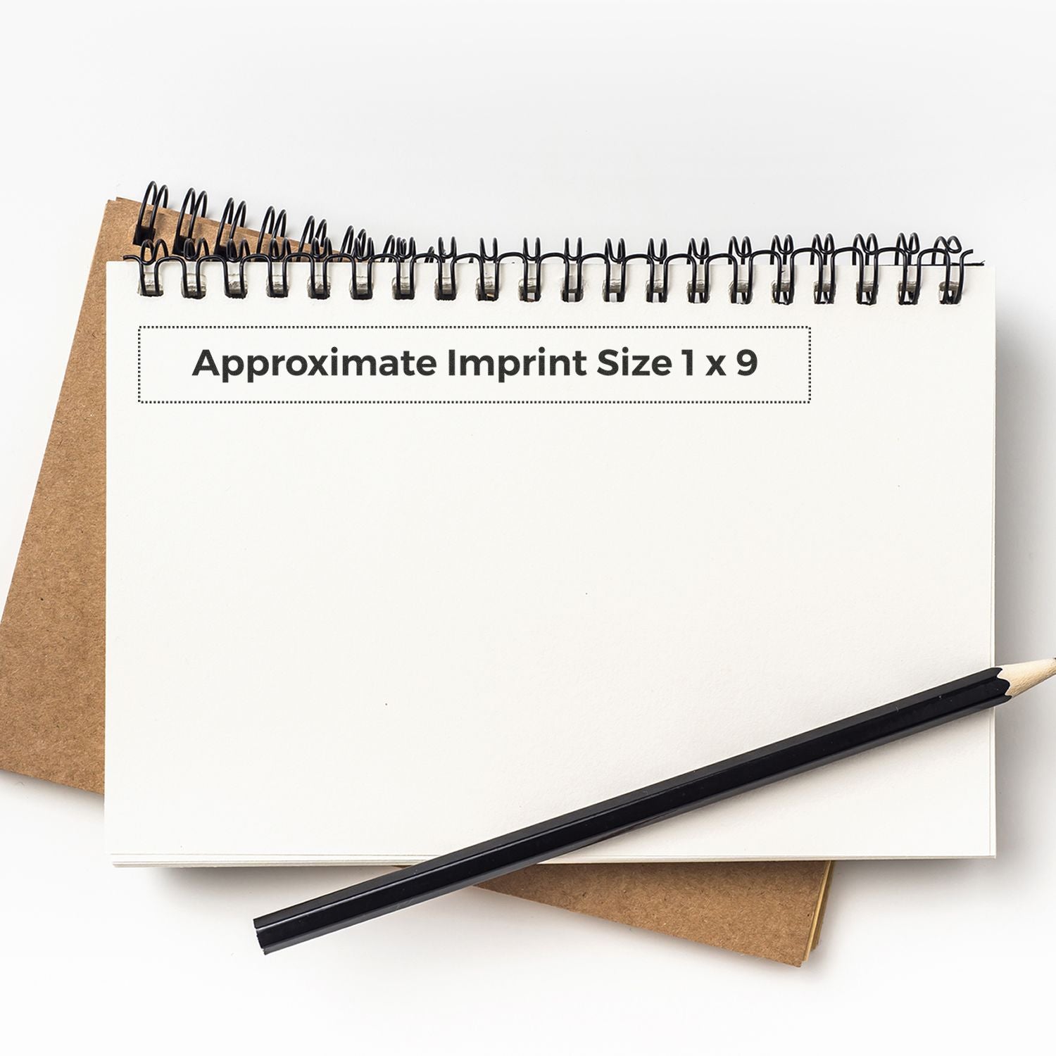 Custom Rubber Stamp Size 1 x 9 shown on a white spiral notebook with a pencil and a brown notebook in the background.