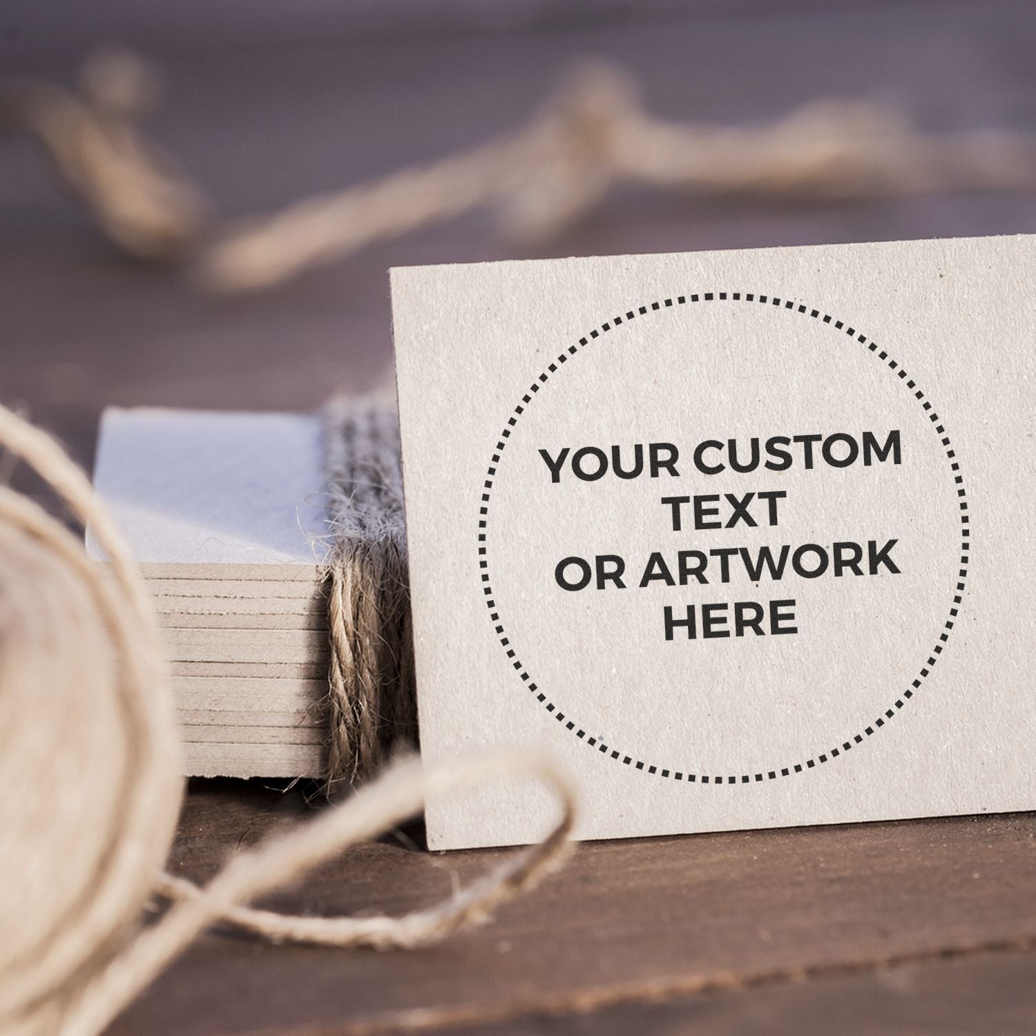 Custom Rubber Stamp Size 2 Inch Diameter imprint on a beige card with Your Custom Text or Artwork Here surrounded by twine and paper.