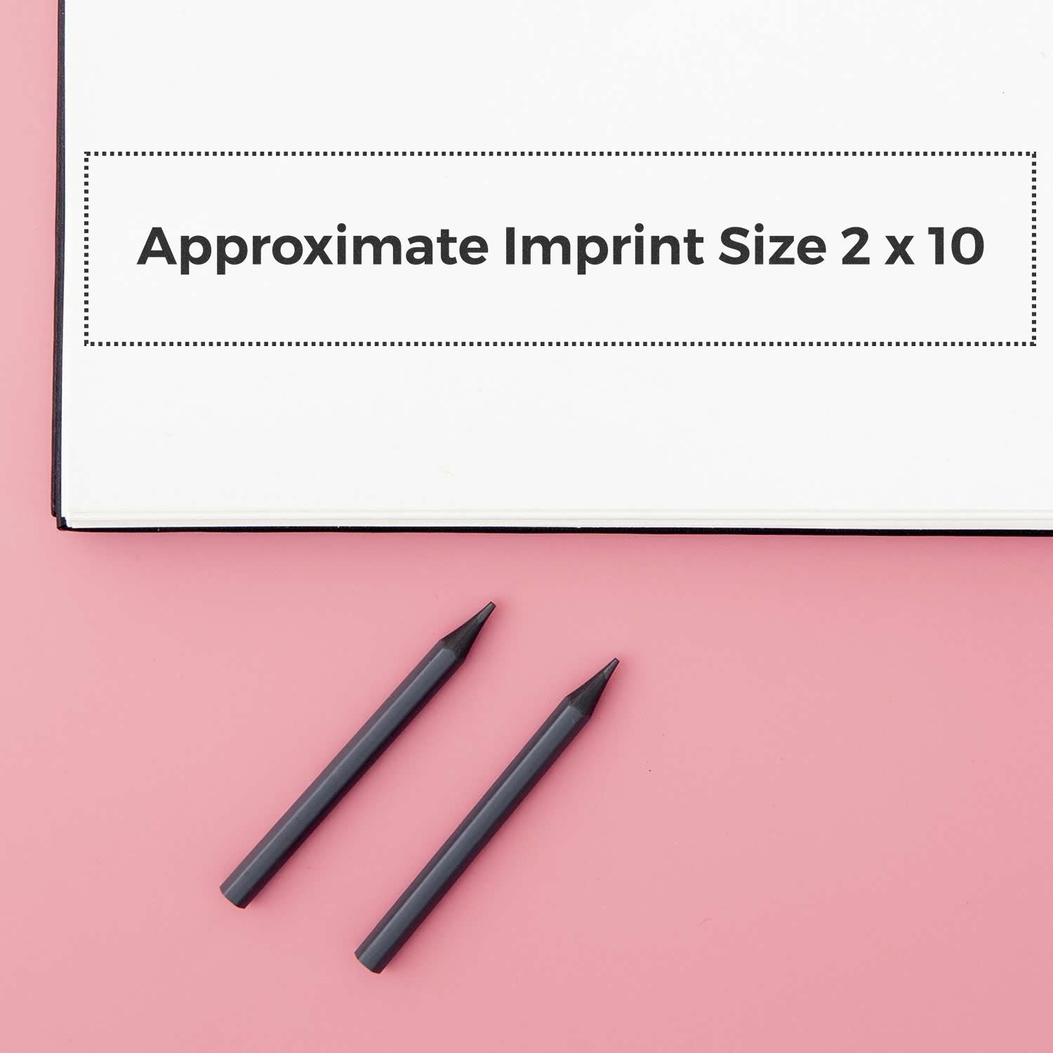 Custom Rubber Stamp Size 2 x 10 shown with approximate imprint size on a white paper, placed on a pink surface with two black pens nearby.