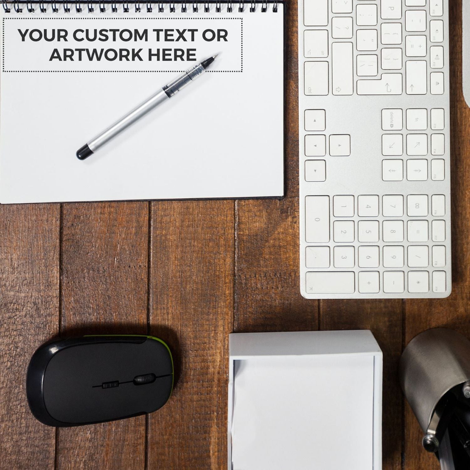 Desk with a Custom Rubber Stamp Size 2 x 9, keyboard, mouse, notepad with Your Custom Text or Artwork Here, pen, and paper stack.