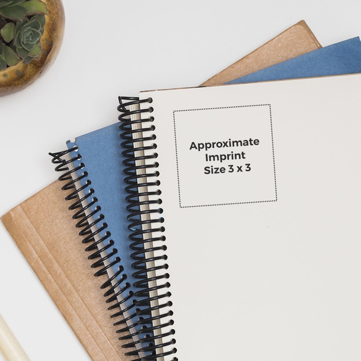Custom Rubber Stamp Size 3 x 3 shown on a white notebook with spiral binding, placed on top of other notebooks and a plant in the background.