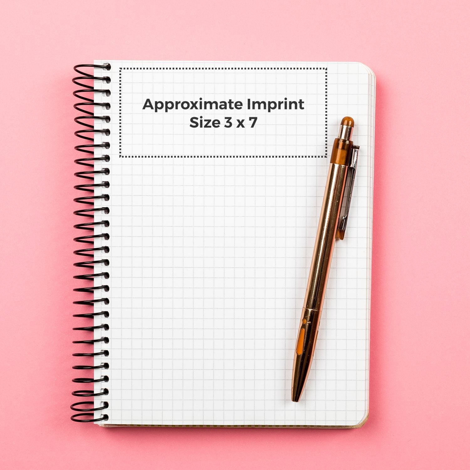 Custom Rubber Stamp Size 3 x 7 shown on a grid notebook with a pen, highlighting the approximate imprint size on a pink background.