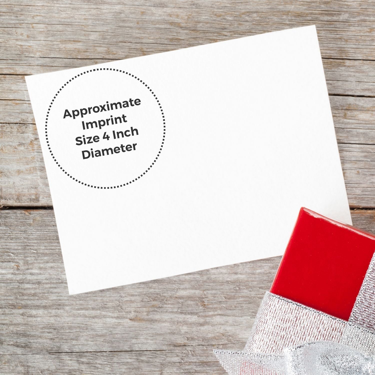 Custom Rubber Stamp Size 4 Inch Diameter imprint on white paper, placed on a wooden surface with a red and silver gift box nearby.