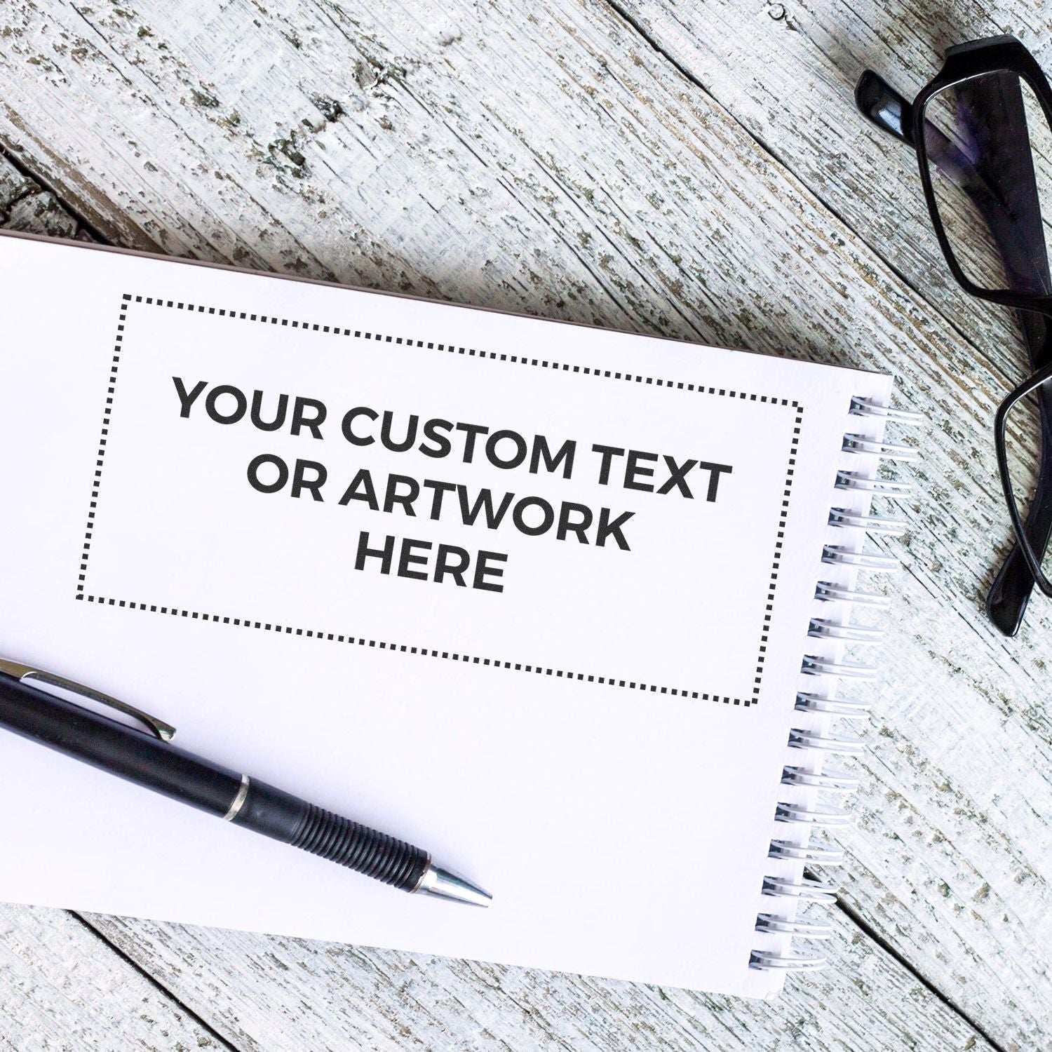 Custom Rubber Stamp Size 4 x 9 stamped on a white notepad with a black pen and glasses on a rustic wooden surface.