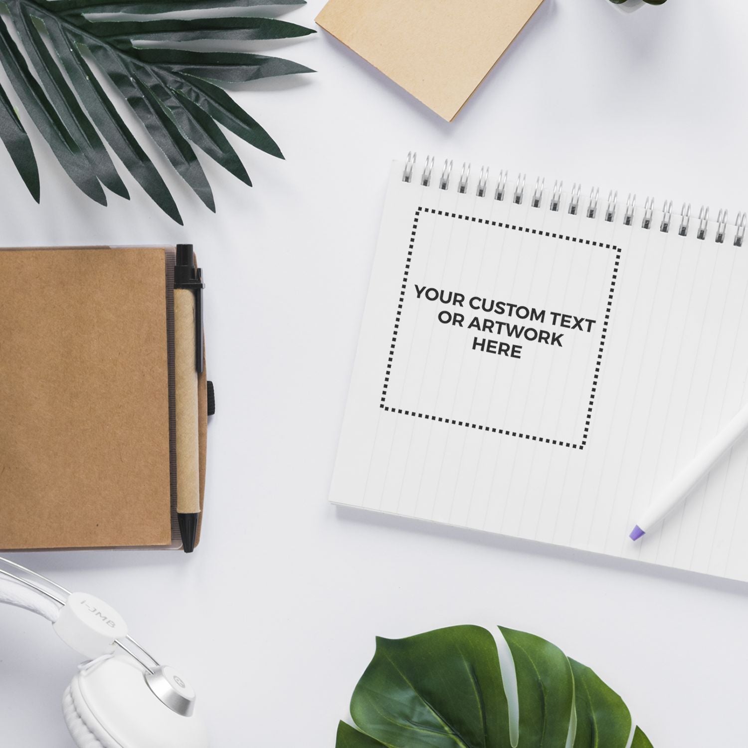 Custom Rubber Stamp Size 5 x 5 stamped on a notebook page with text YOUR CUSTOM TEXT OR ARTWORK HERE, surrounded by office supplies and plants.