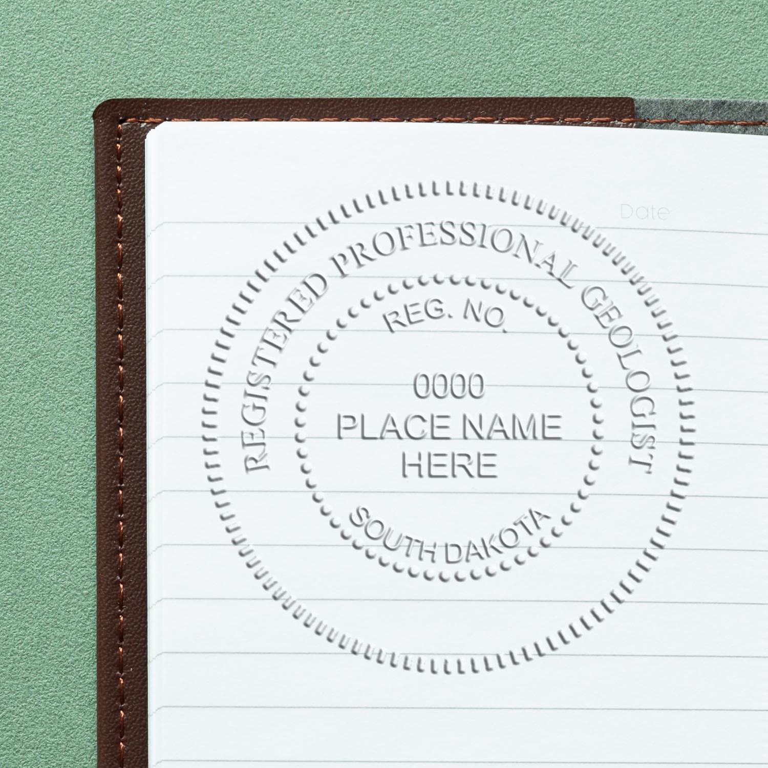 A lifestyle photo showing a stamped image of the Heavy Duty Cast Iron South Dakota Geologist Seal Embosser on a piece of paper