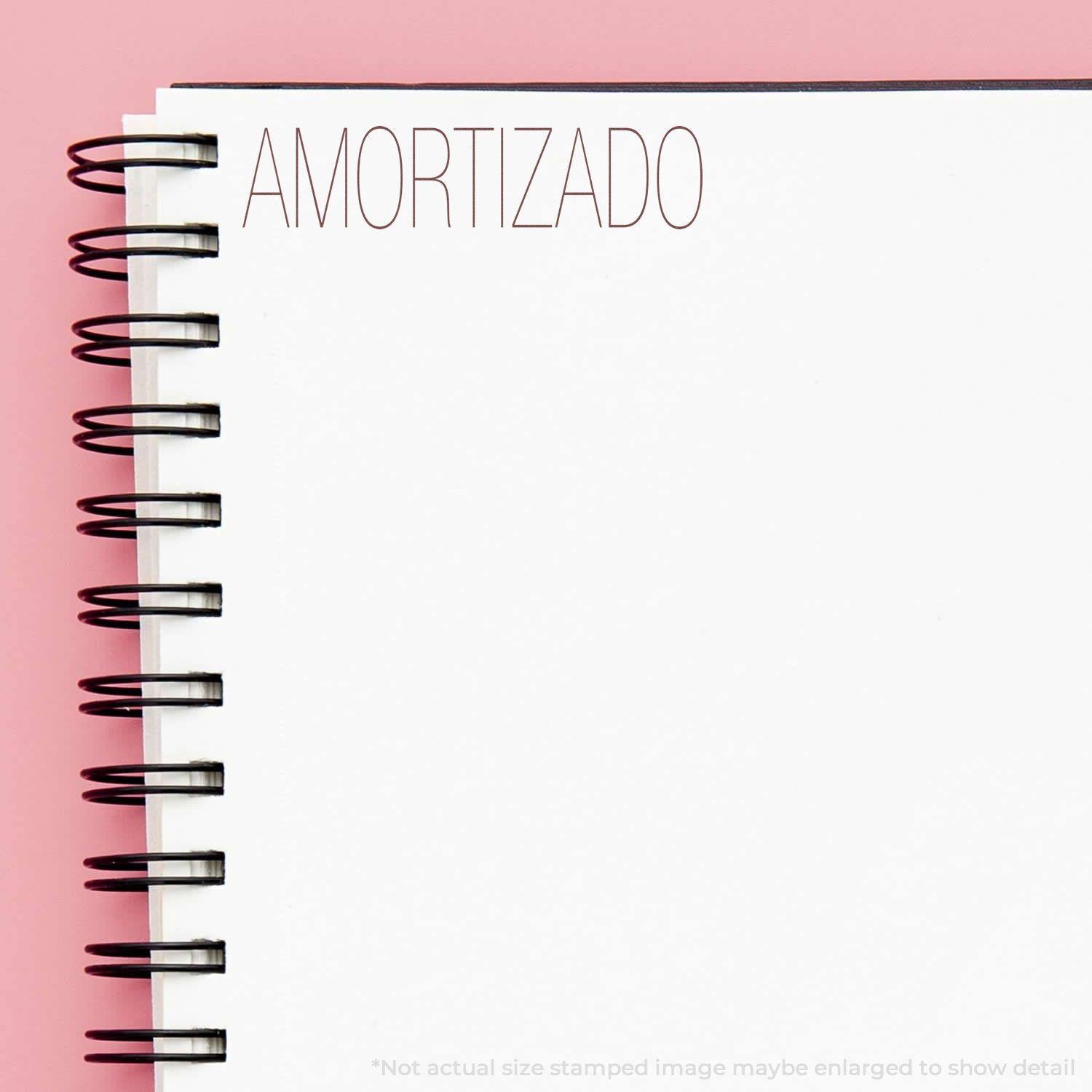 Slim Pre-Inked Amortizado Stamp used on a white spiral notebook with AMORTIZADO stamped in the top left corner.
