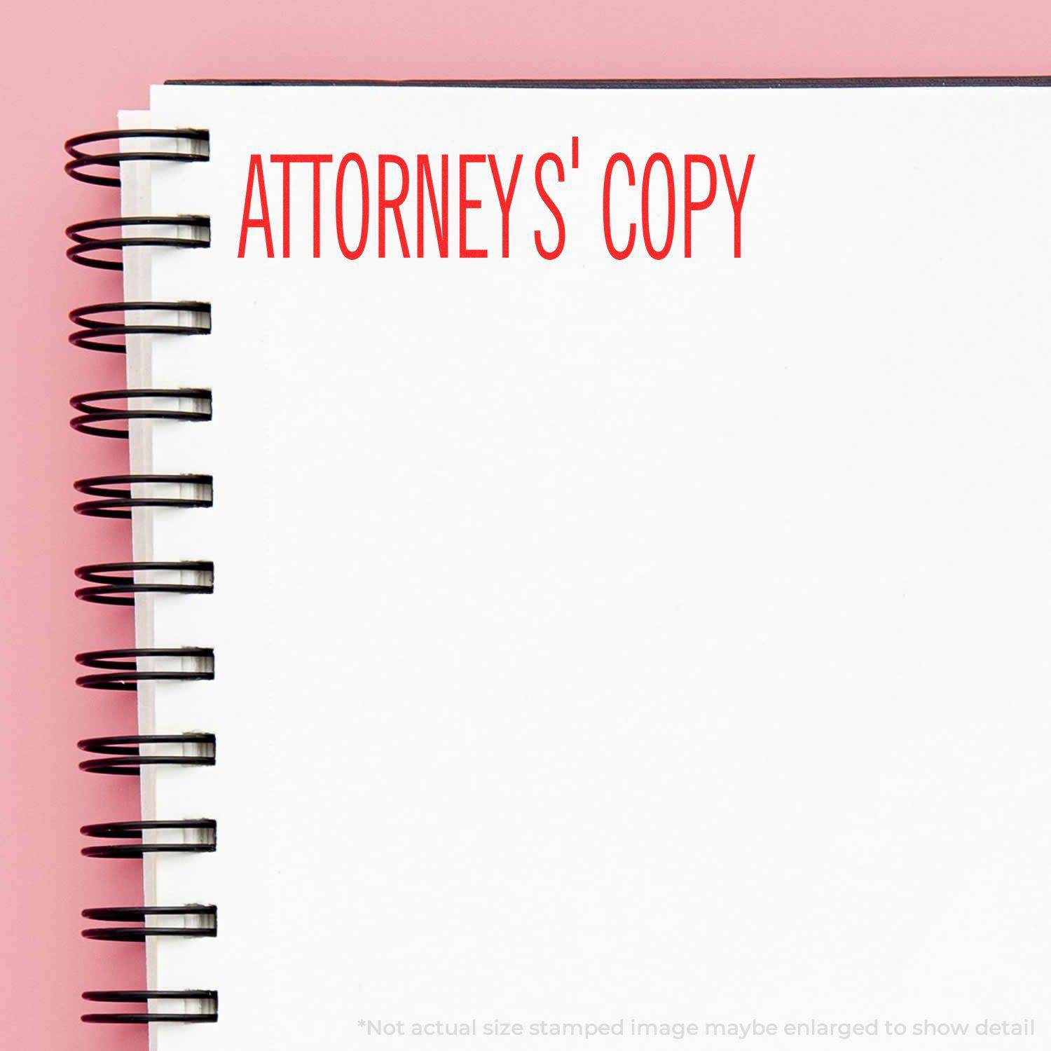 Large Pre-Inked Attorney's Copy Stamp in red ink on a white spiral notebook with a pink background.