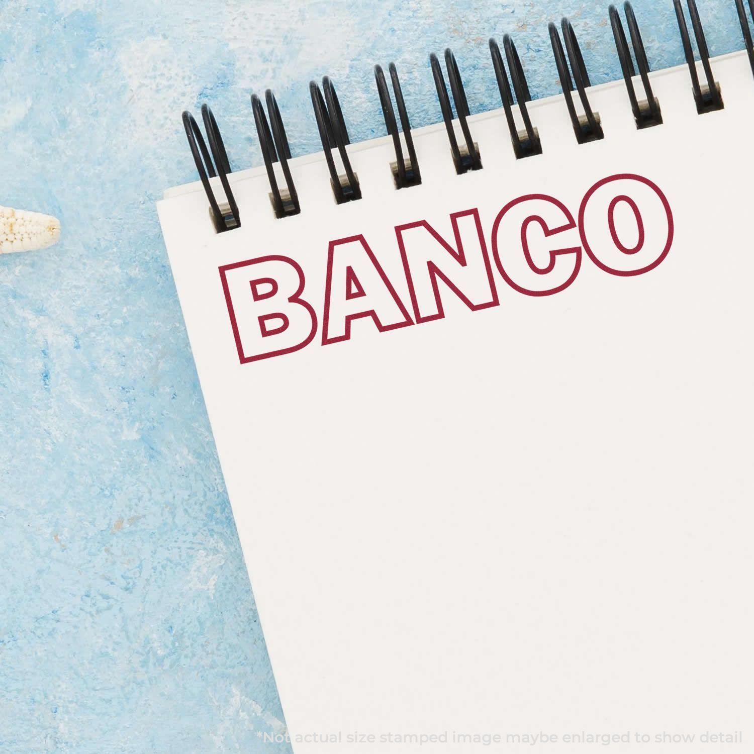 Notebook with 'BANCO' stamped in red using a Slim Pre-Inked Banco Stamp on a blue textured background.