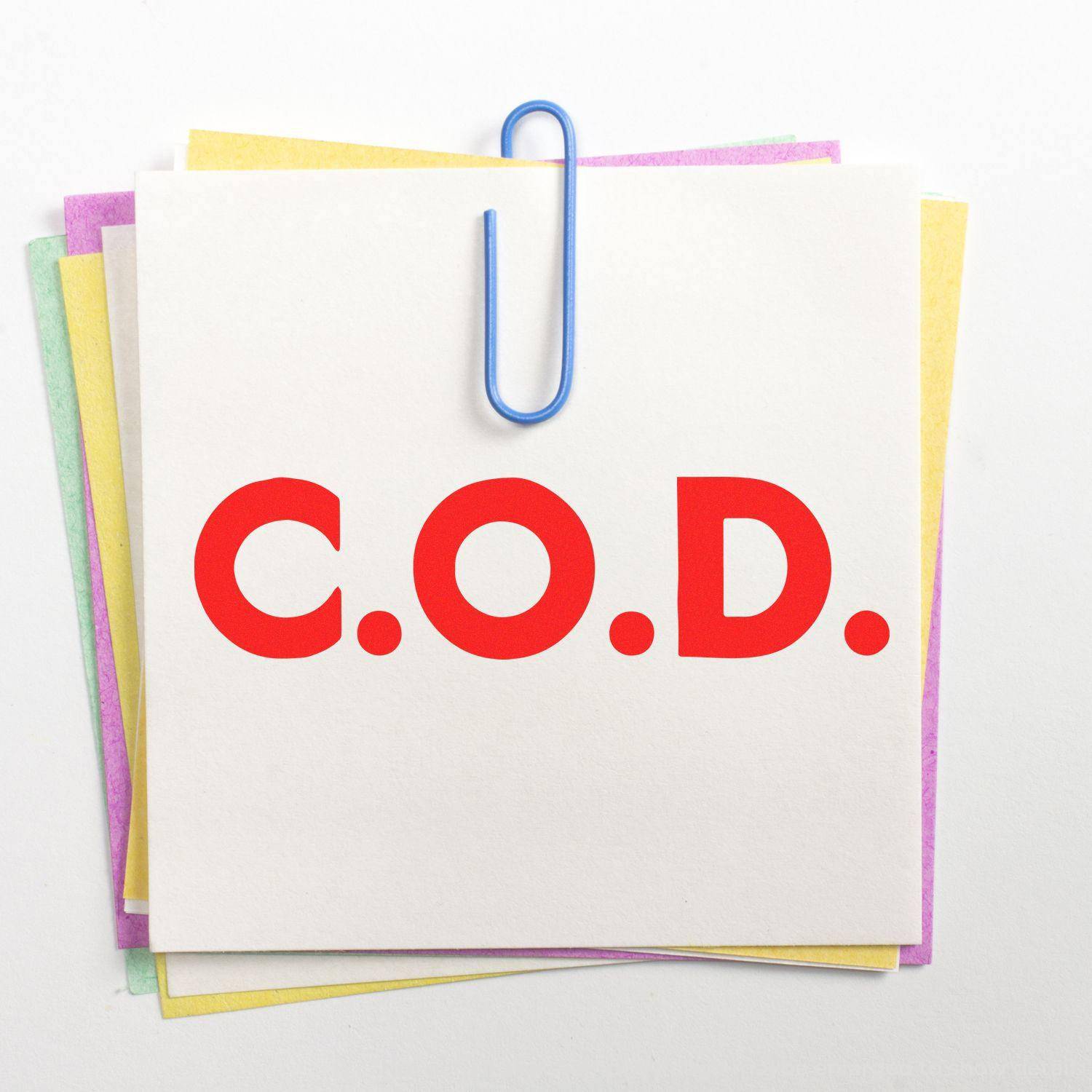 Large Pre-Inked Bold COD Stamp imprint on a stack of colorful sticky notes held together by a blue paperclip.