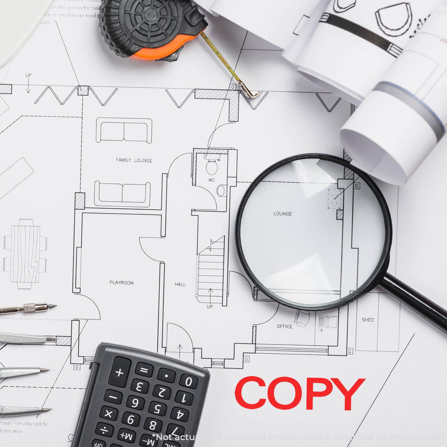 Large Self Inking Bold Copy Stamp marking COPY in red on architectural plans, surrounded by a magnifying glass, calculator, and measuring tape.