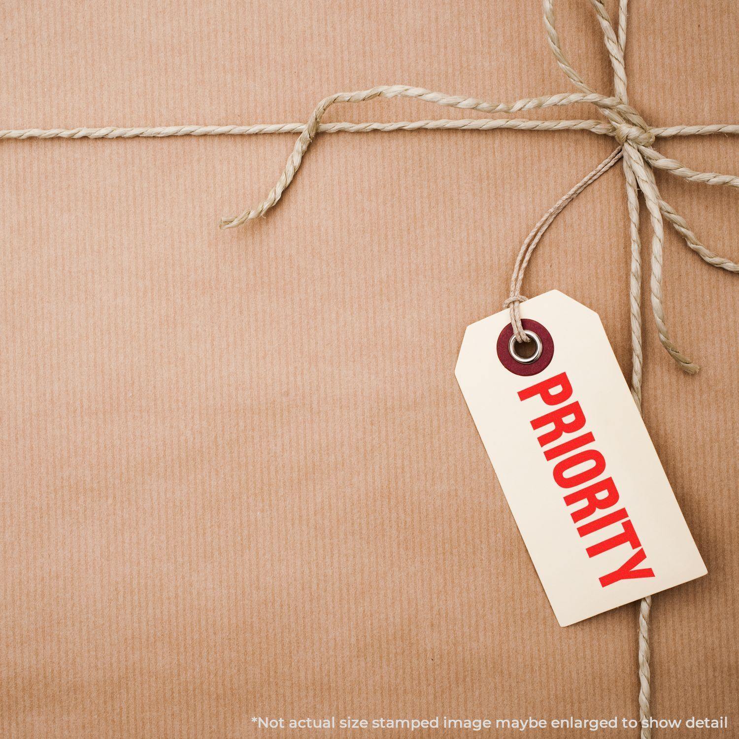A package wrapped in brown paper and twine with a tag labeled PRIORITY stamped in red using a Bold Priority Rubber Stamp.