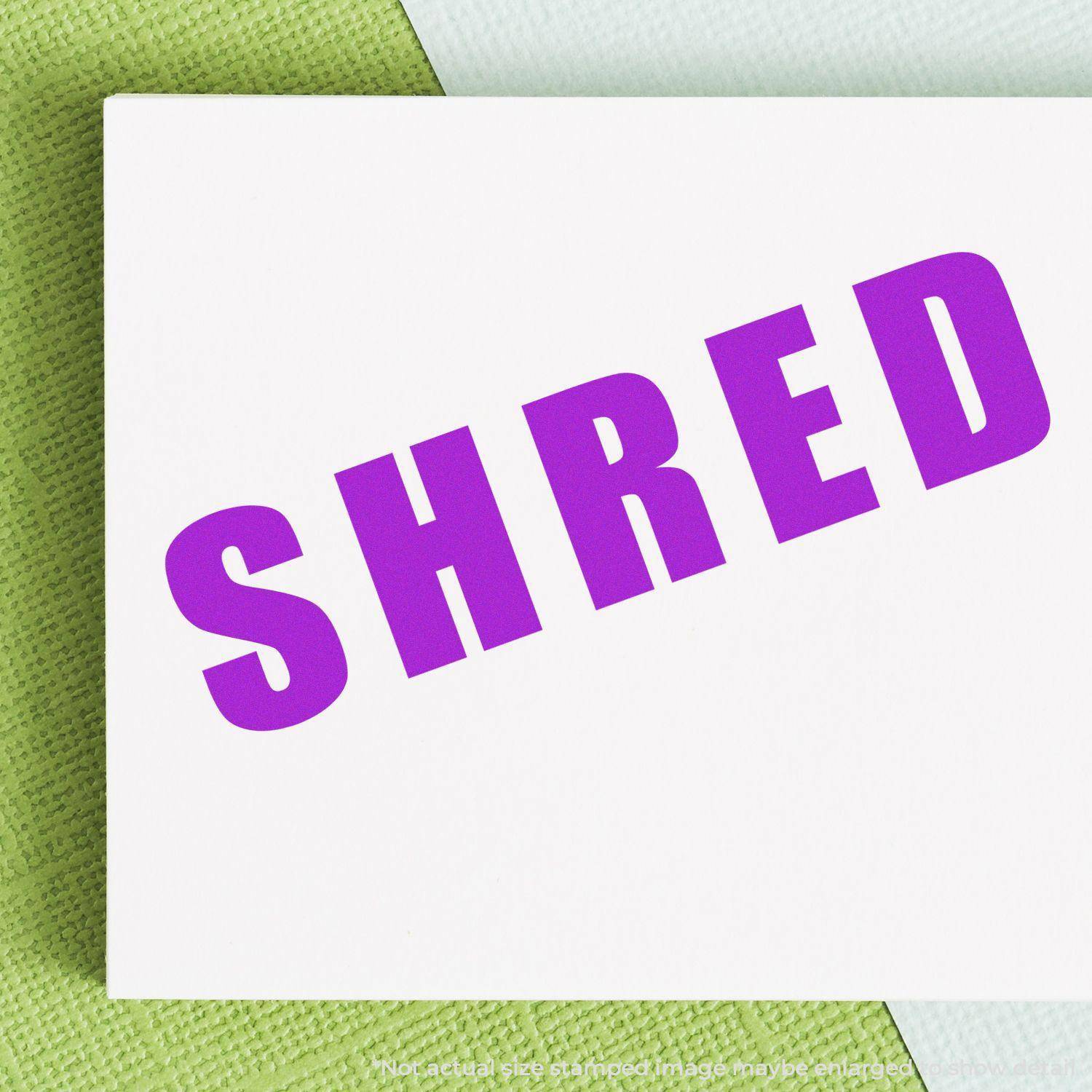 Large Self Inking Bold Shred Stamp in use, displaying the word SHRED in bold purple letters on a white paper background.