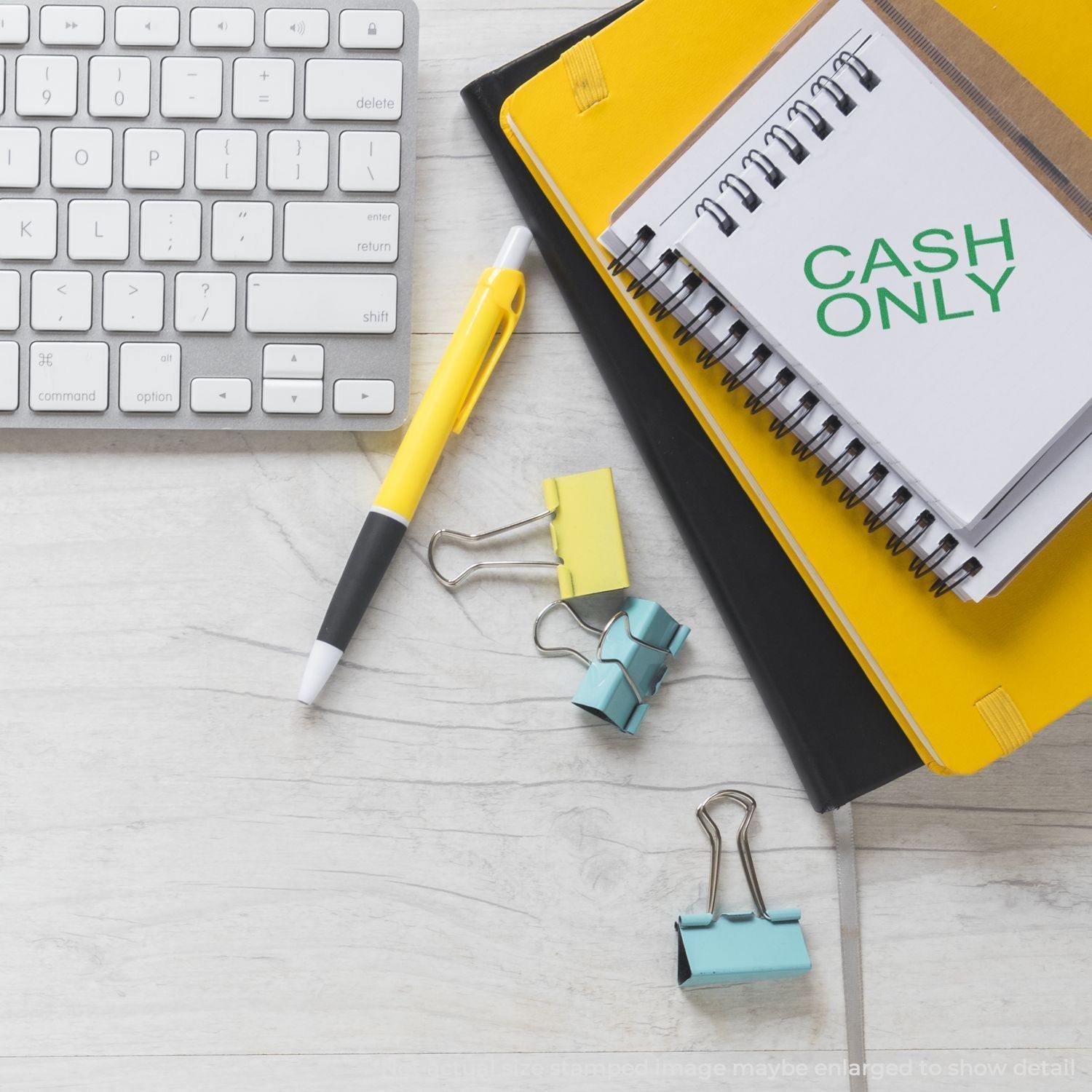 Slim Pre-Inked Cash Only Stamp on a notebook, surrounded by a keyboard, pen, yellow binder, and colorful binder clips.