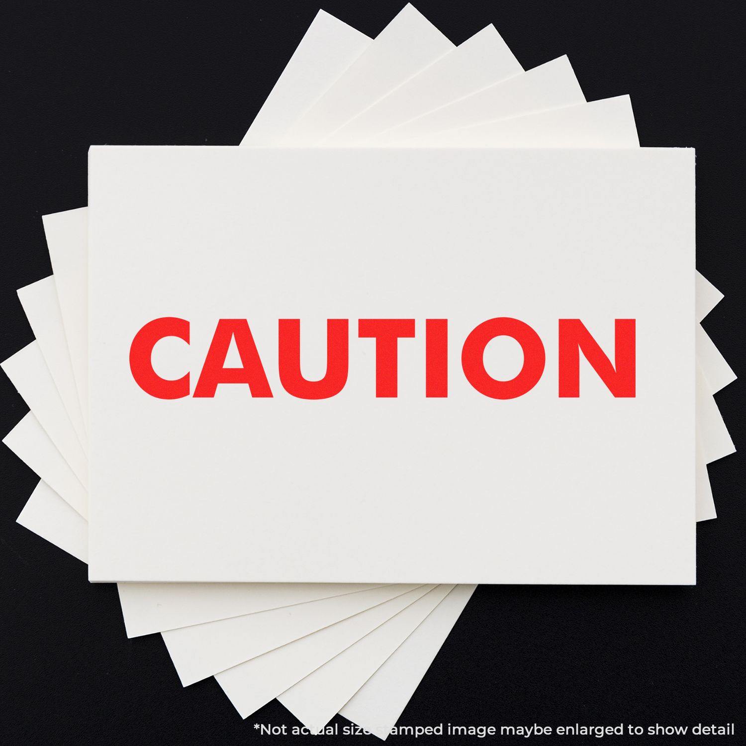 Slim Pre-Inked Caution Stamp in red ink on a white card, with multiple cards fanned out underneath on a black background.