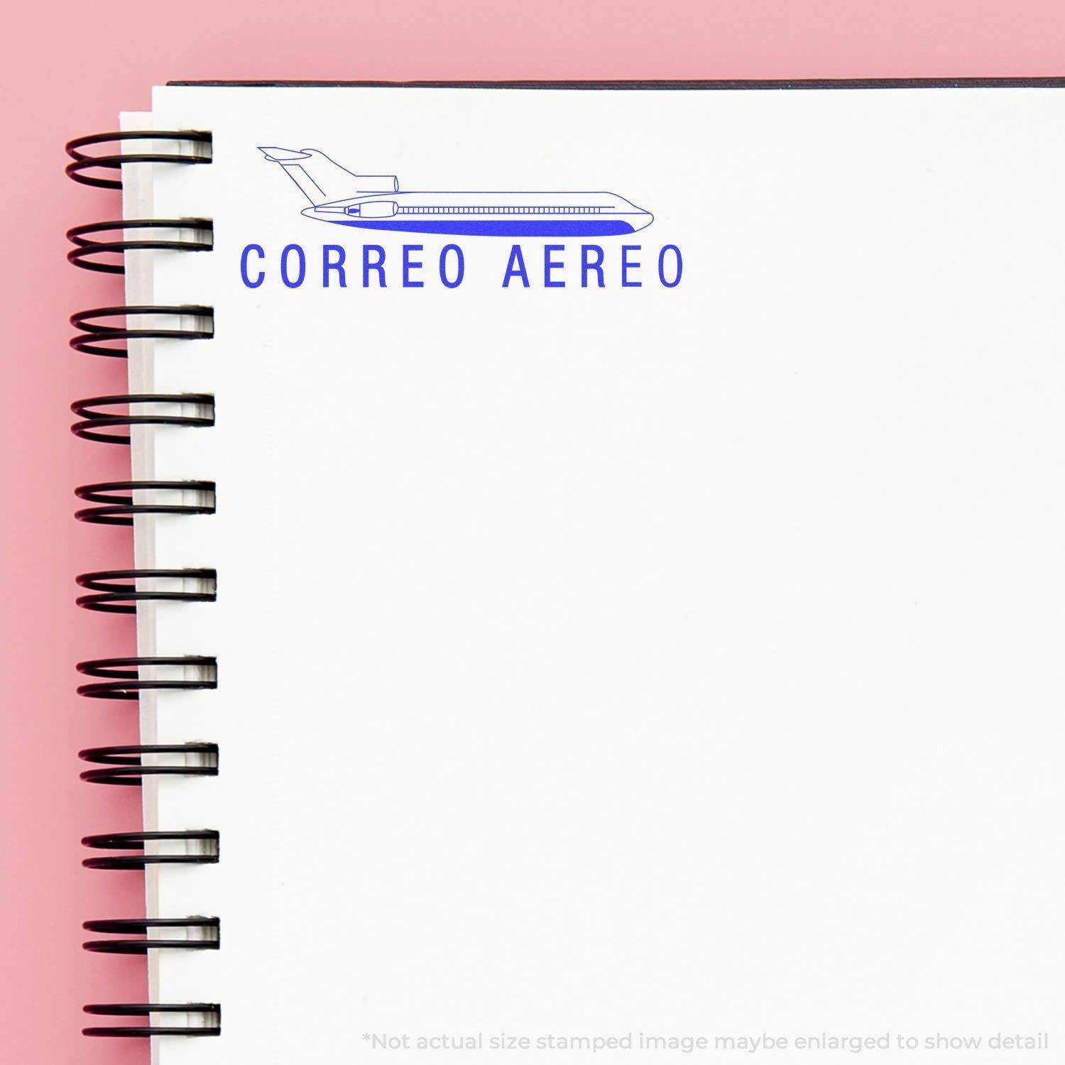 Large Pre-Inked Correo Aero Stamp imprint on a white spiral notebook page with a pink background, showing a blue airplane and text CORREO AEREO .