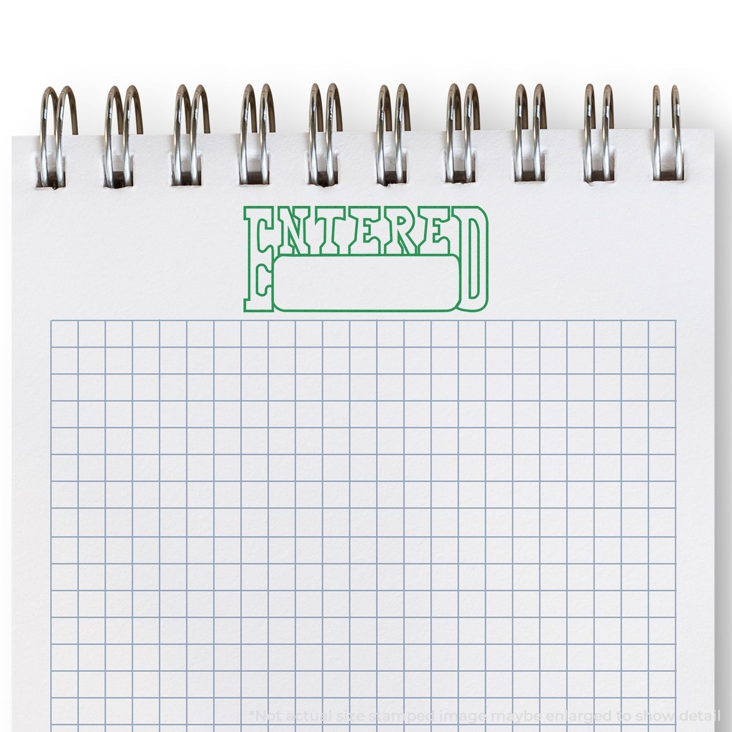 Slim Pre-Inked Entered with Date Box Stamp imprint in green ink on a spiral-bound graph paper notebook.