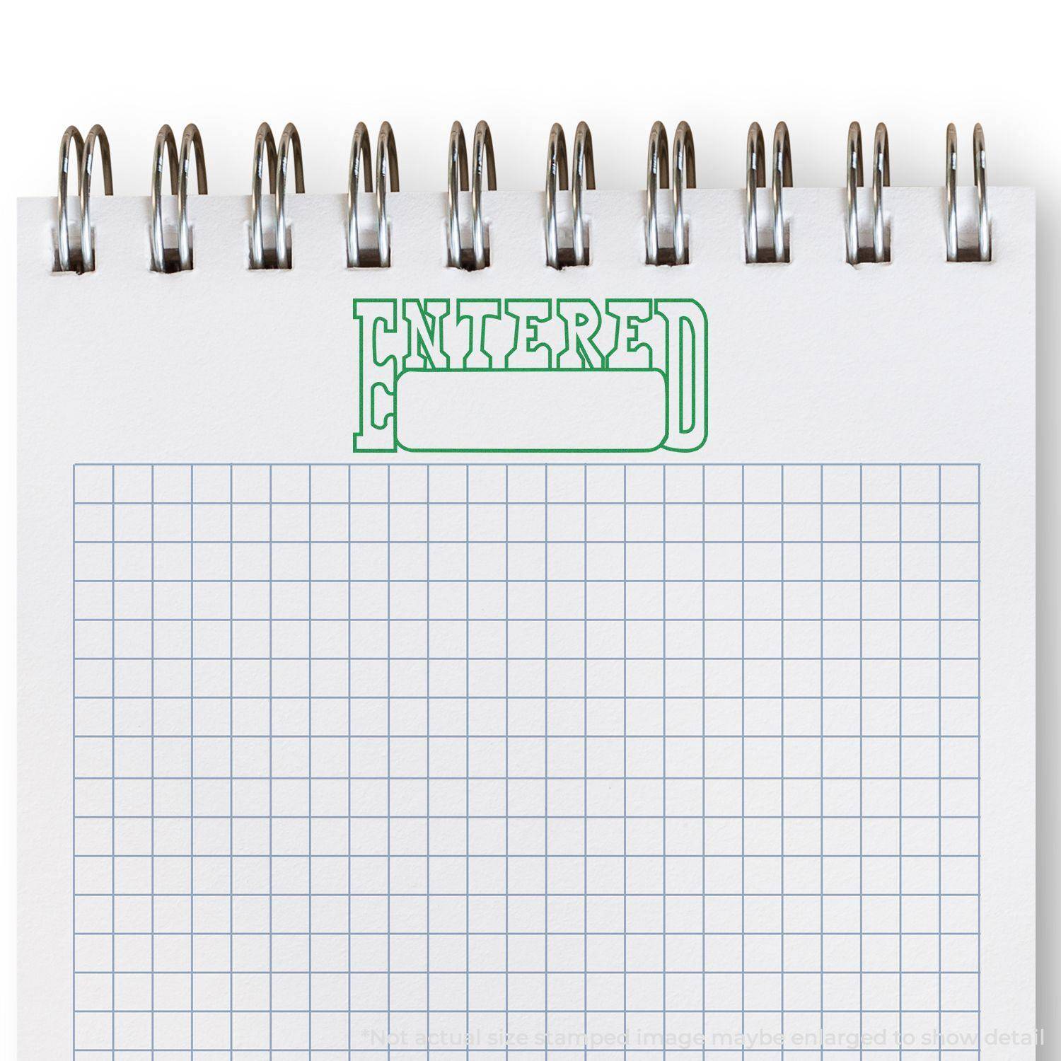 Large Pre-Inked Entered with Date Box Stamp in green ink on a spiral-bound graph paper notebook.