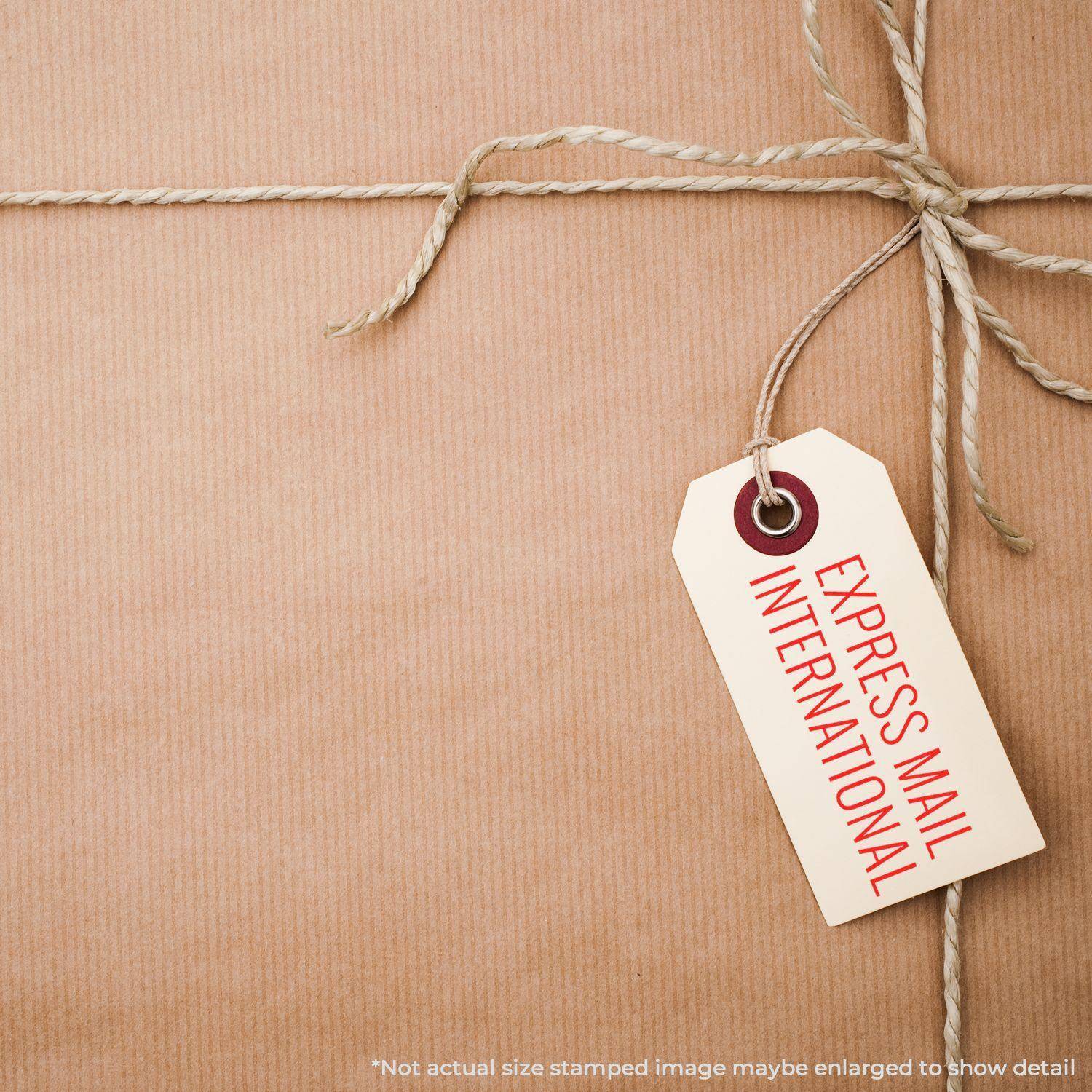 A brown package tied with string and a tag stamped with EXPRESS MAIL INTERNATIONAL using the Large Pre-Inked Express Mail International Stamp.