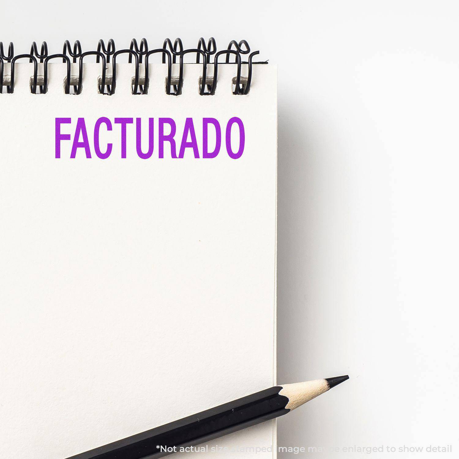 Large Pre-Inked Facturado Stamp imprint in purple on a white notepad with a black pencil beside it.