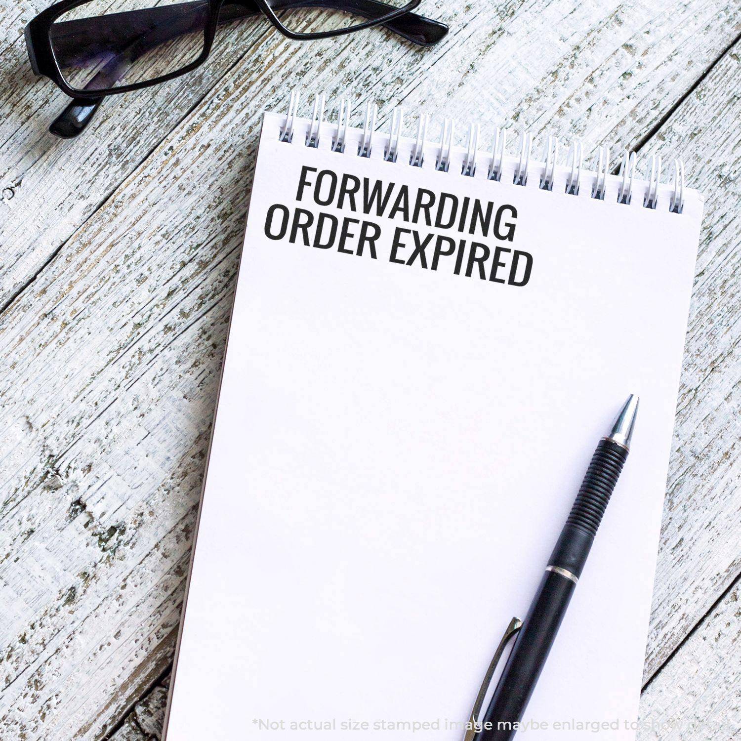 Large Pre-Inked Forwarding Order Expiring Stamp used on a notepad with FORWARDING ORDER EXPIRED text, next to a pen and glasses.