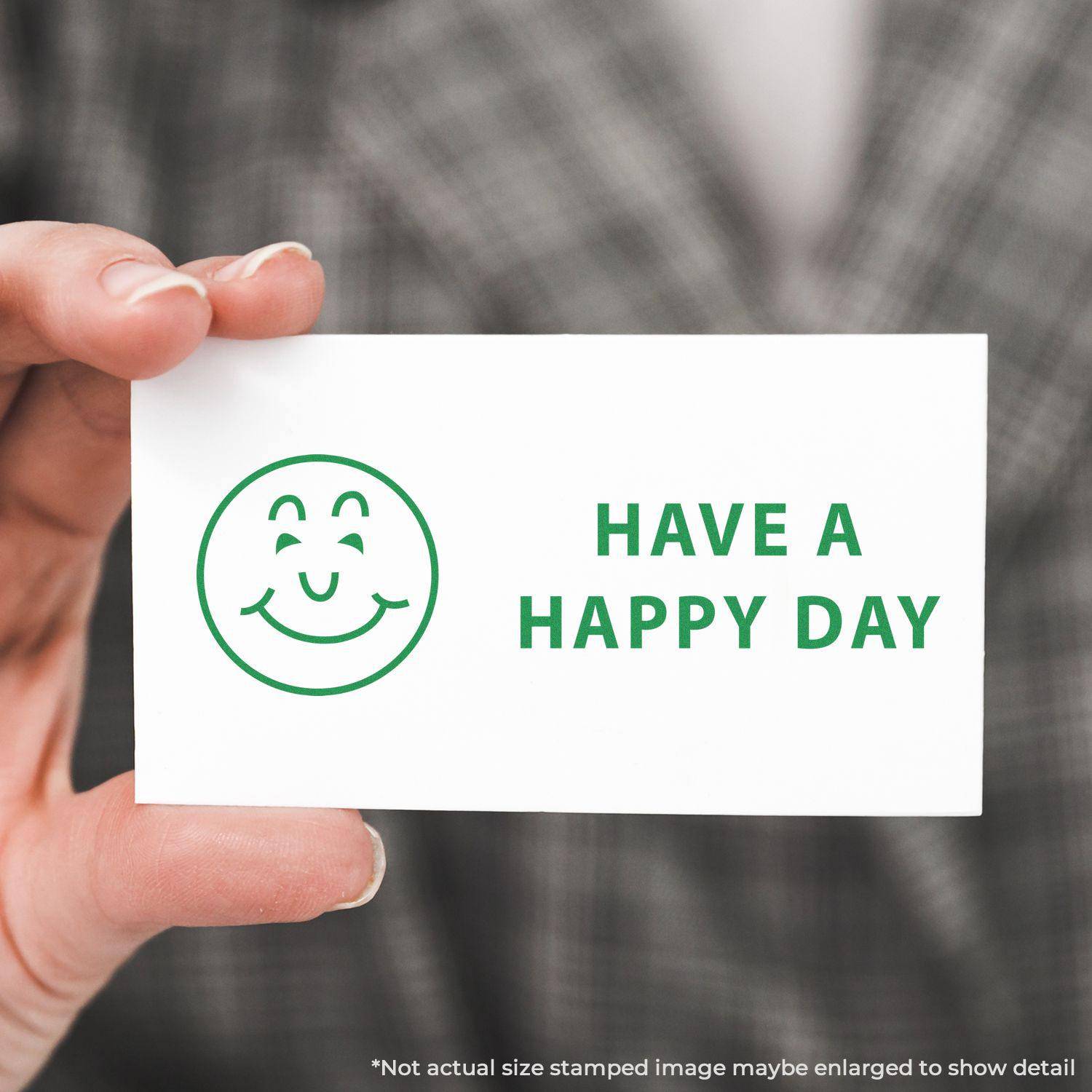 A hand holding a card stamped with a green smiley face and the text HAVE A HAPPY DAY using the Large Pre-Inked Have a Happy Day Stamp.