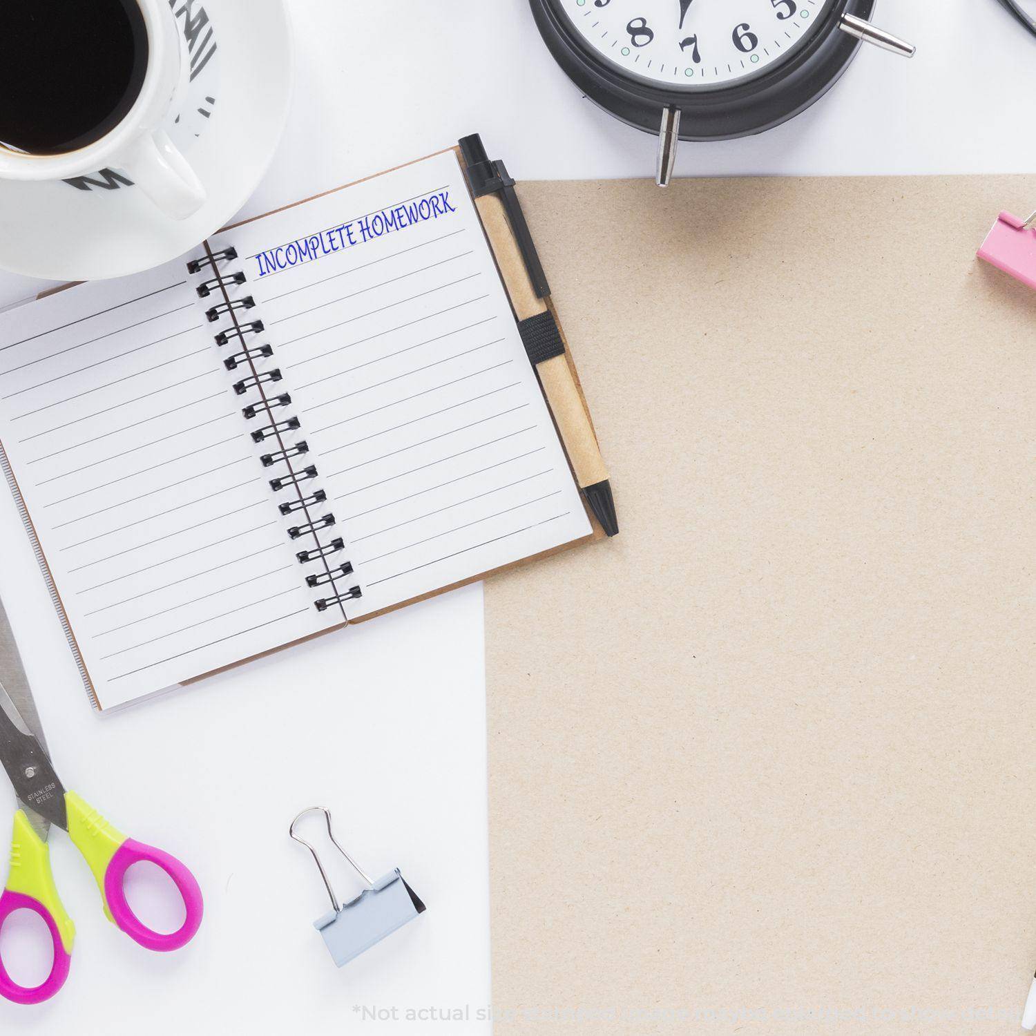 Large Pre-Inked Incomplete Homework Stamp used on a notebook, surrounded by a clock, coffee cup, scissors, and office supplies.