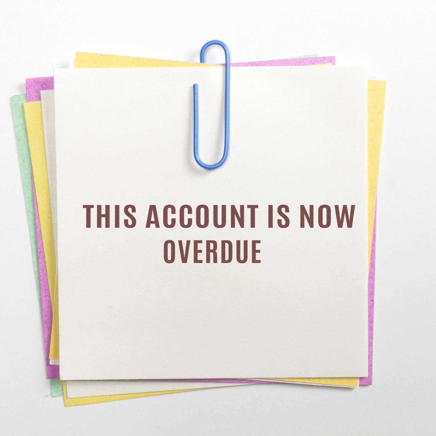 A stack of colorful sticky notes clipped together with a blue paperclip, featuring the Large Narrow This Account Is Now Overdue Rubber Stamp.
