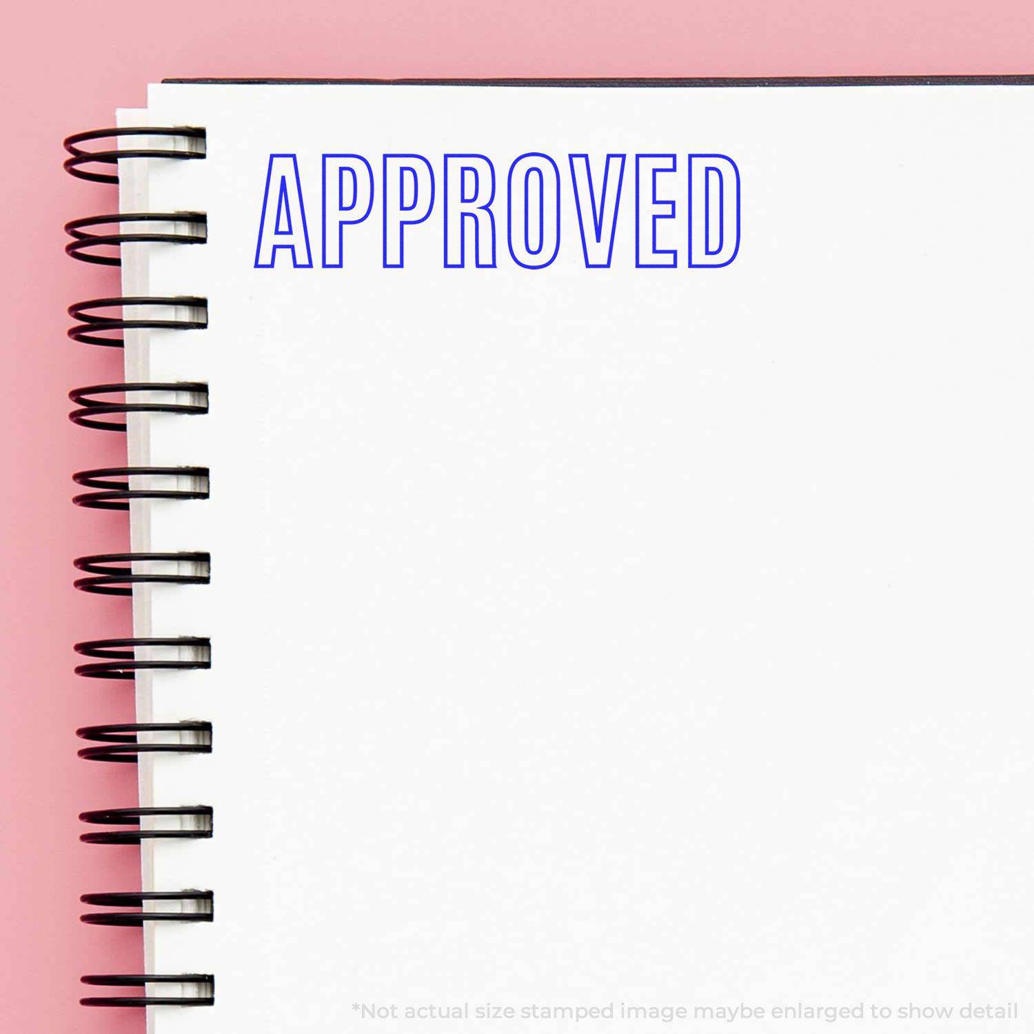 Large Outline Approved Rubber Stamp used on a white notebook with a spiral binding, displaying the word APPROVED in blue ink.