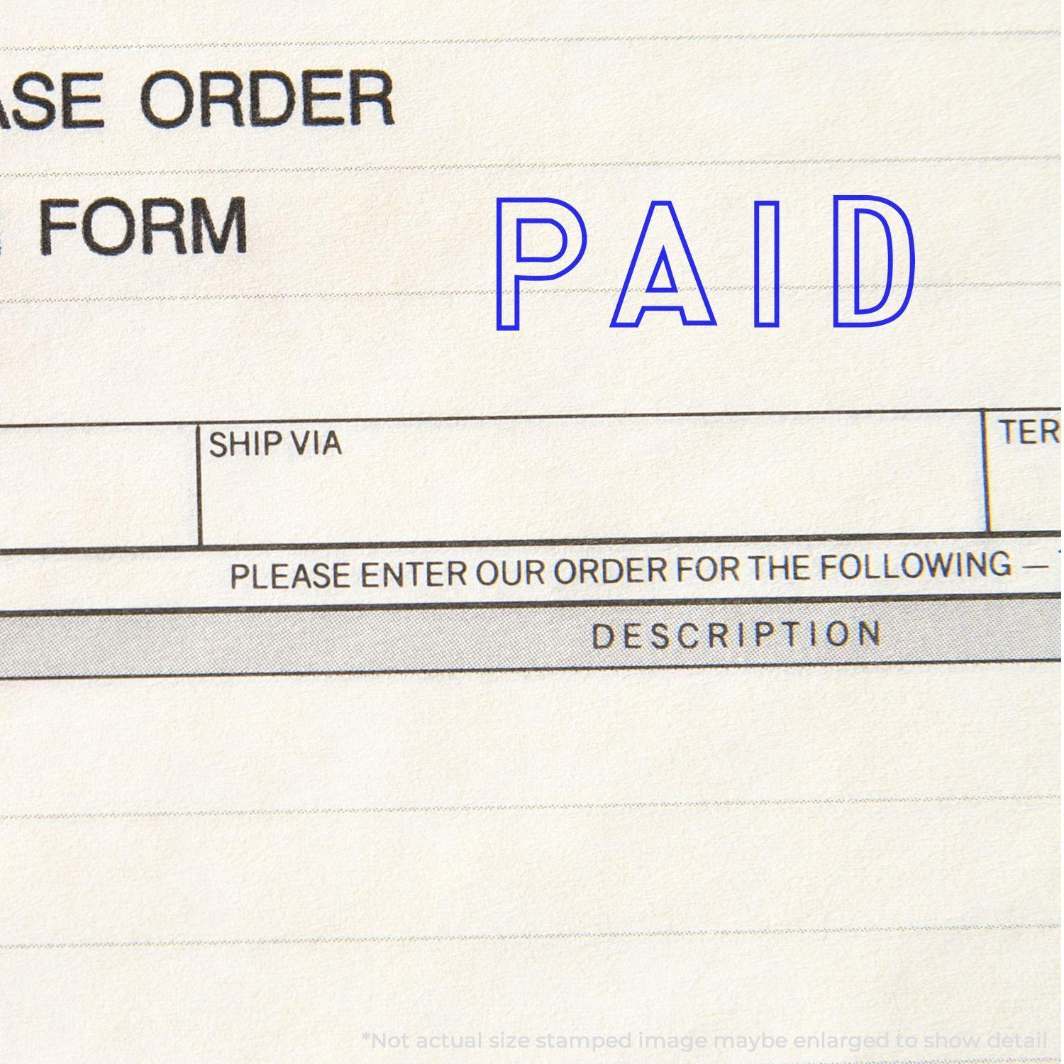 A stock office rubber stamp with a stamped image showing how the text "PAID" in an outline font is displayed after stamping.