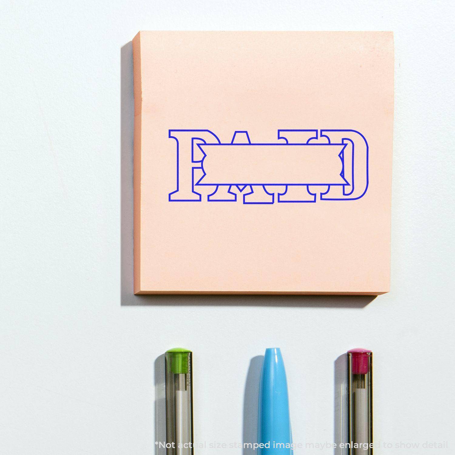 Large Paid with Box Rubber Stamp imprint on a pink sticky note, with three pens below.