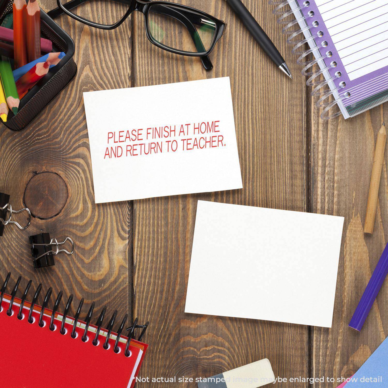 Desk with stationery and a card stamped with 'PLEASE FINISH AT HOME AND RETURN TO TEACHER' using the Large Please Finish At Home And Return To Teacher Rubber Stamp.